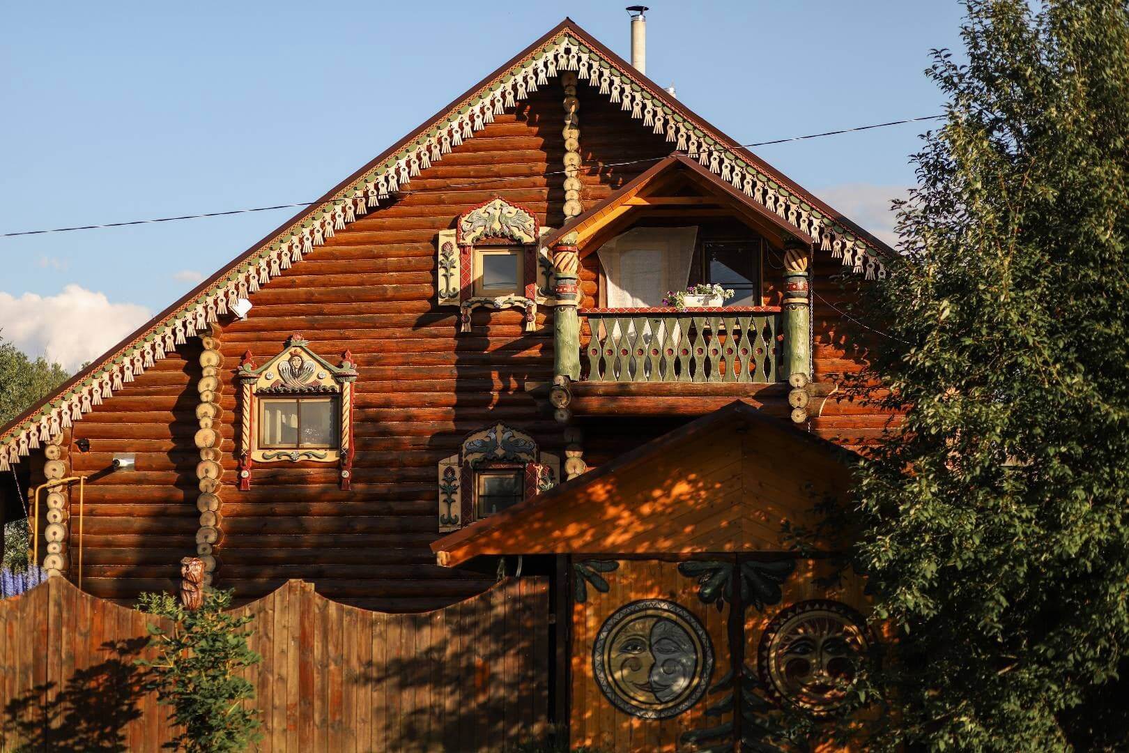 Красивый фасад деревянного дома с воротами.