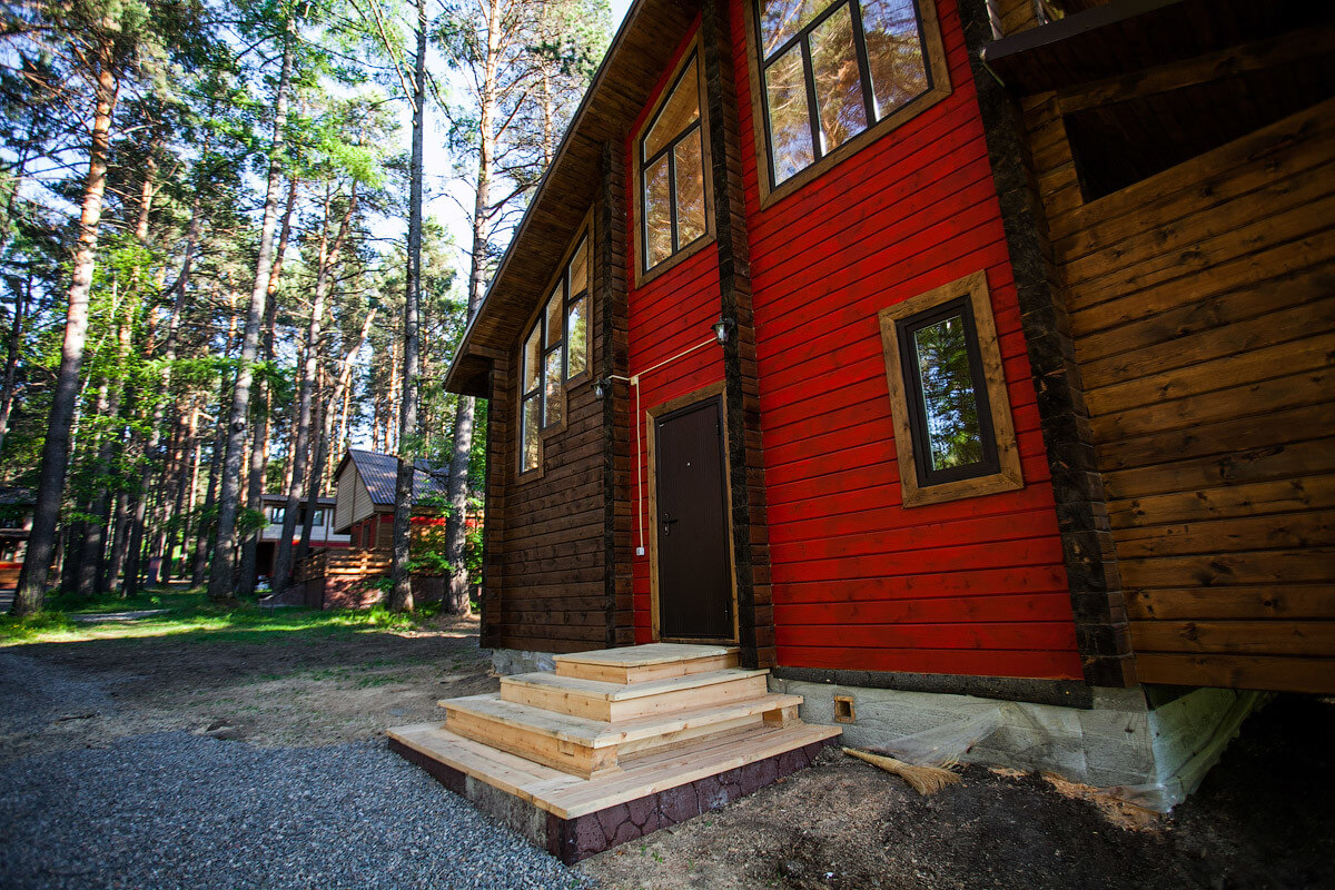 Дом с ярким, красным фасадом в лесу.