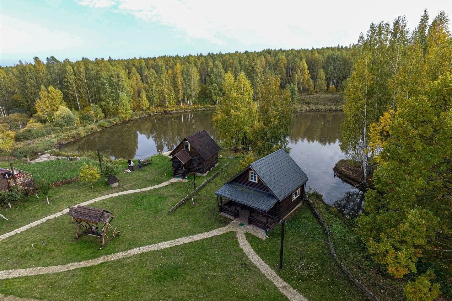 Панорамный вид: деревянные дома и небольшой пруд.