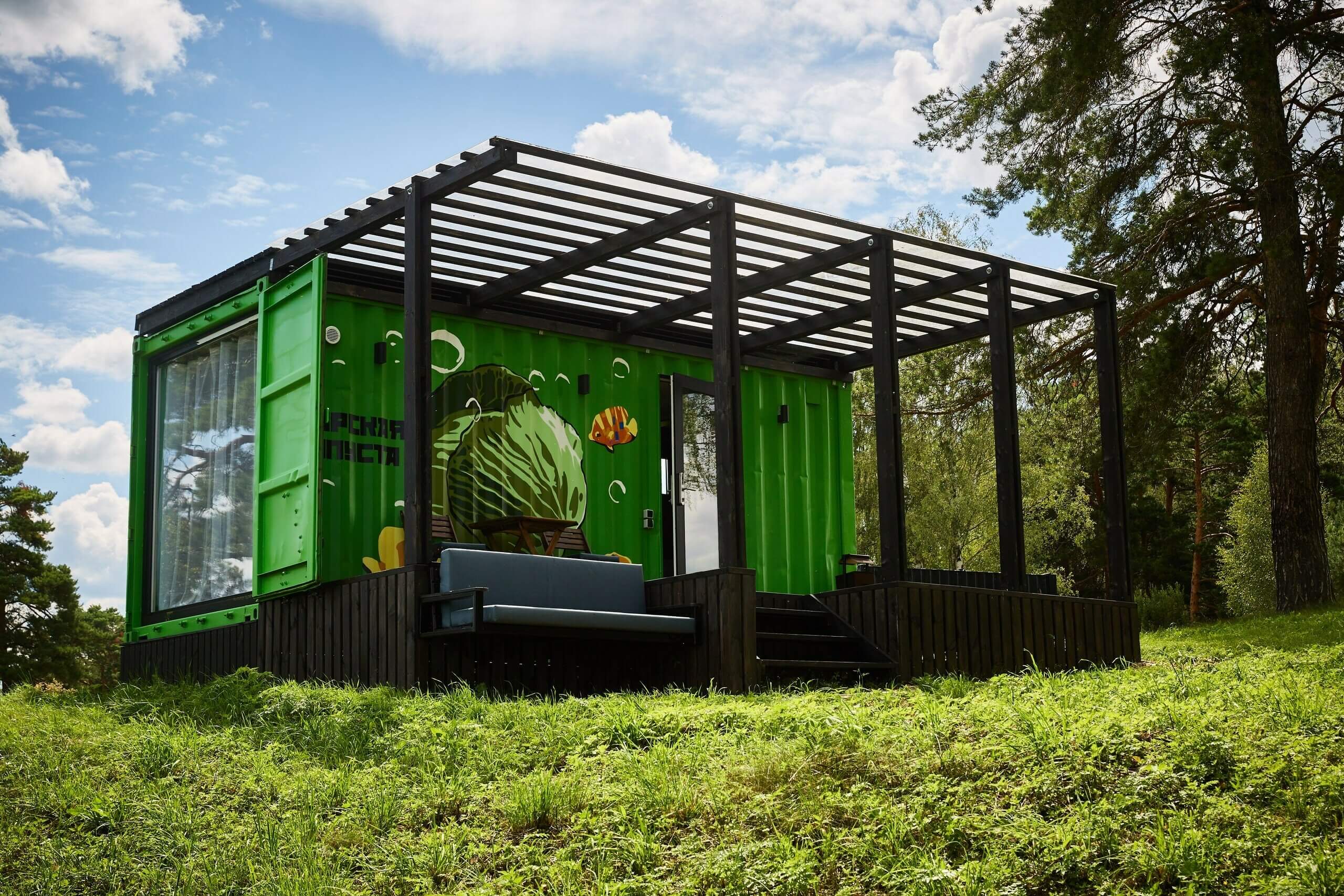 Фасад домика-контейнера выкрашен в зеленый цвет.