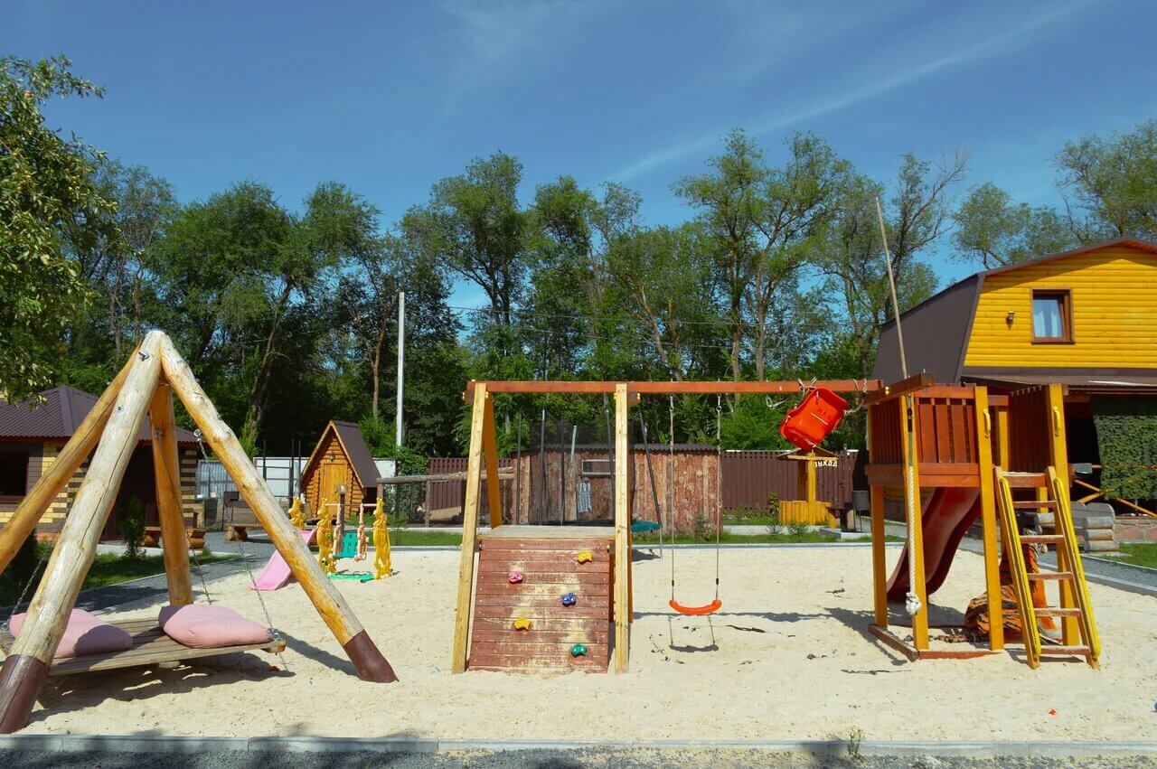 Детская площадка: качели, горка, домики и песочница.