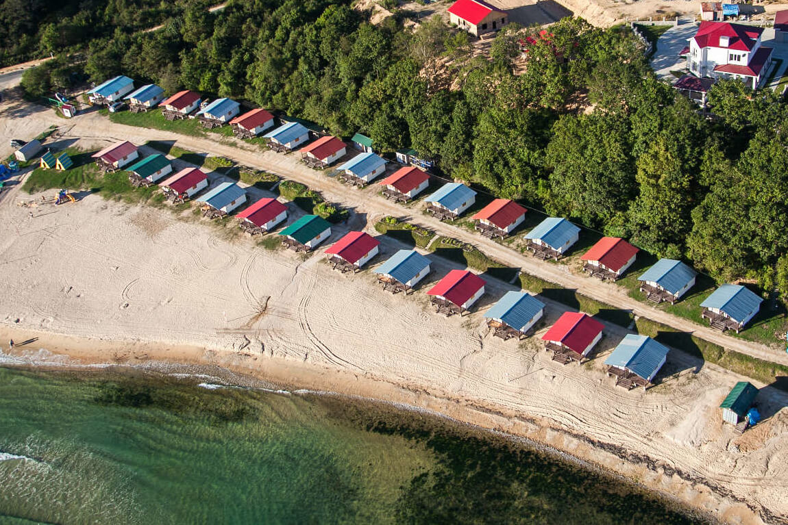 Панорамный вид с высоты птичьего полета: пляж и домики с разноцветными крышами.