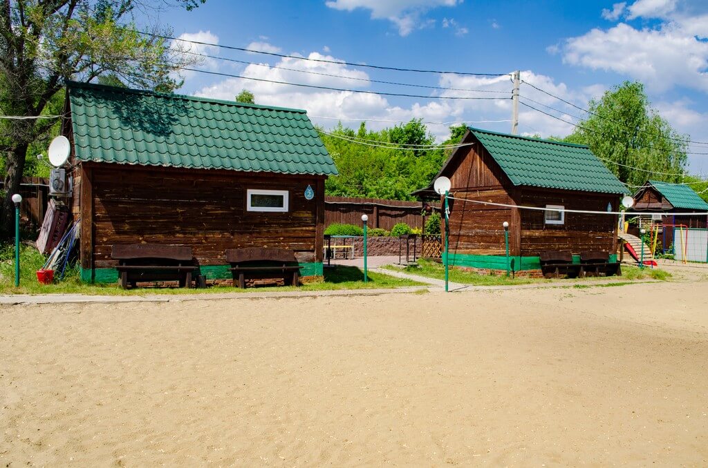 Небольшие домики и волейбольная площадка с песчаным покрытием.