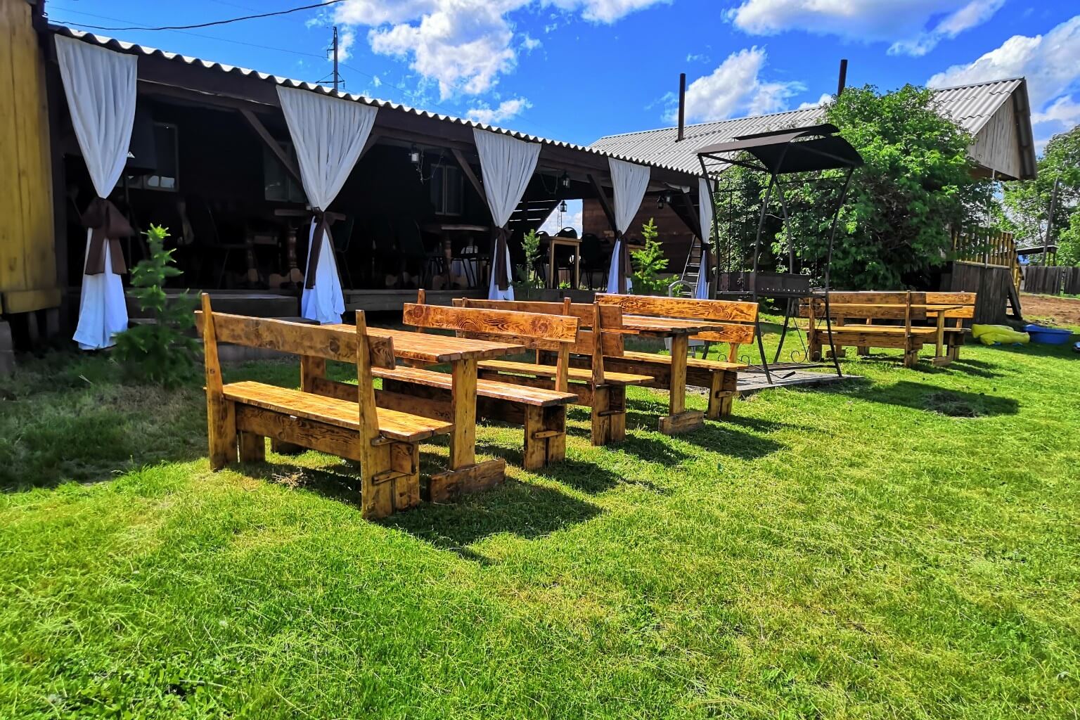 Кафе-терраса, лавочки и столики на зеленом газоне.