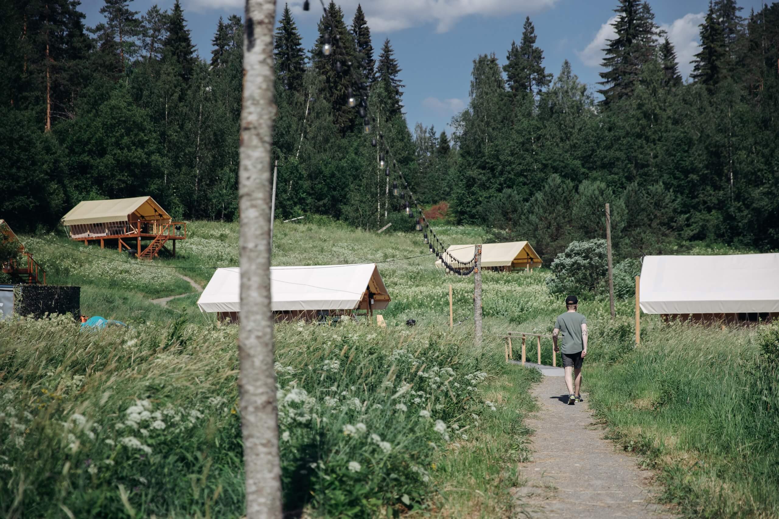 Лесная поляна на склоне перед лесом и шатры-палатки.