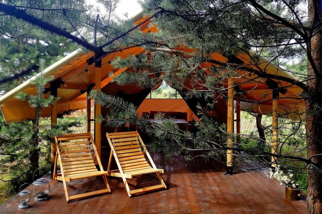 На подиуме перед палаткой установлены деревянные кресла-шезлонги.