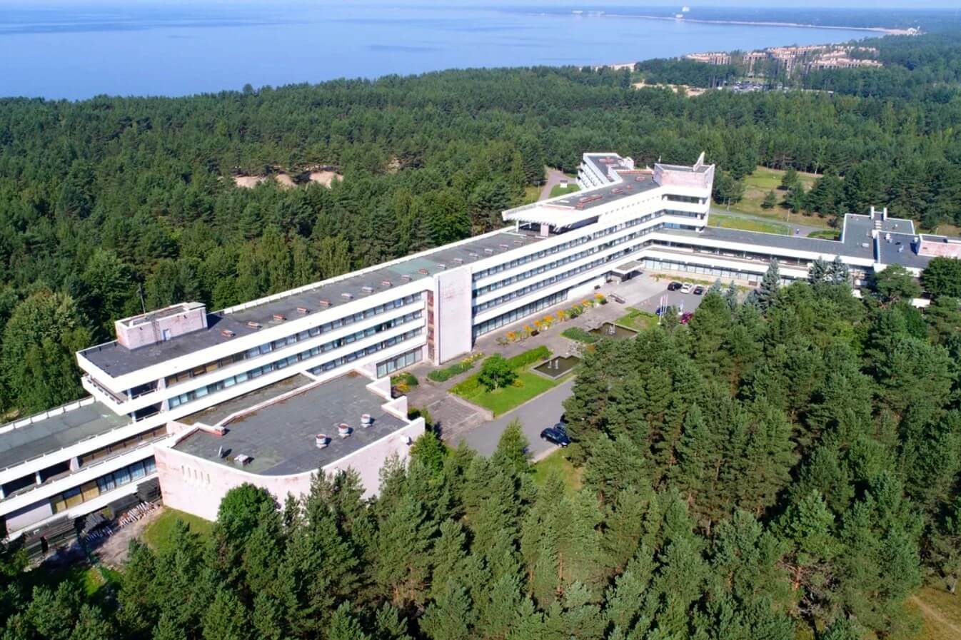 Вид с высоты на огромный корпус санатория. Вдали - Финский залив.