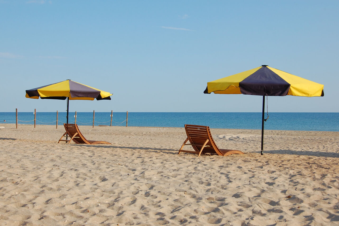 Пляж и море. Два одиноких зонтика и шезлонга.