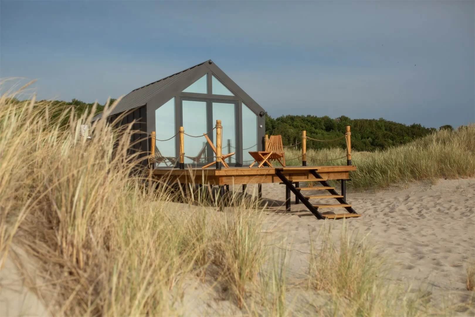 Пляж, песок и домик с террасой.