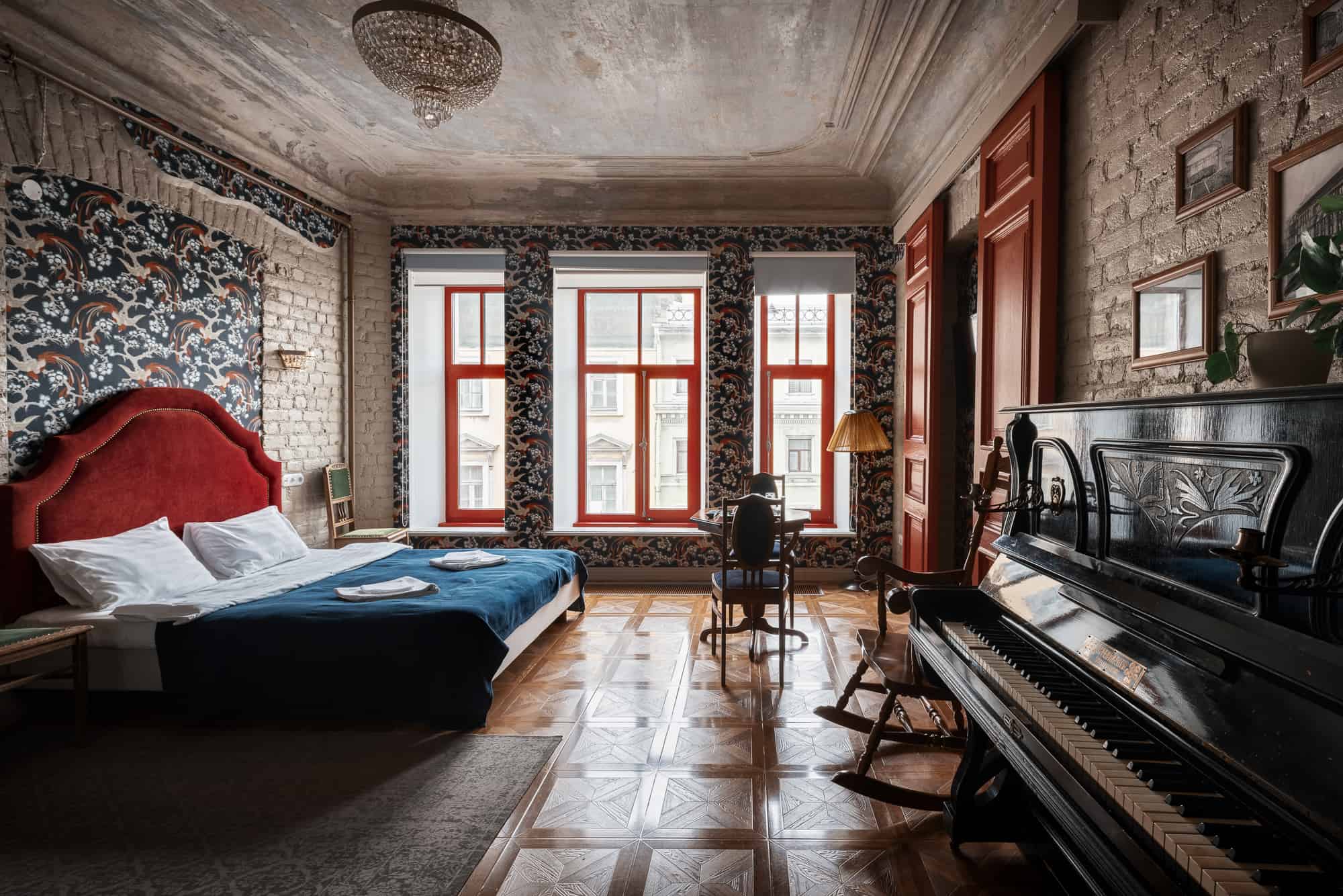 Большая кровать, пианино, кресло-качалка и три окна на все стену.