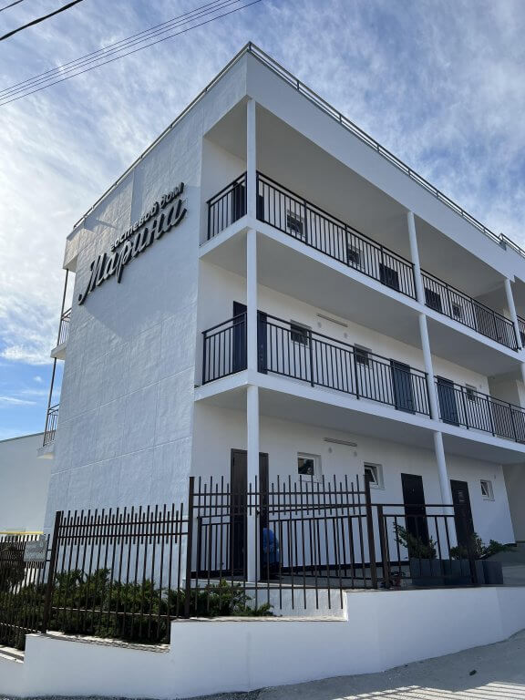 Стены отеля - белого цвета, На боковом фасаде большая вывеска: "Гостевой дом Марина".