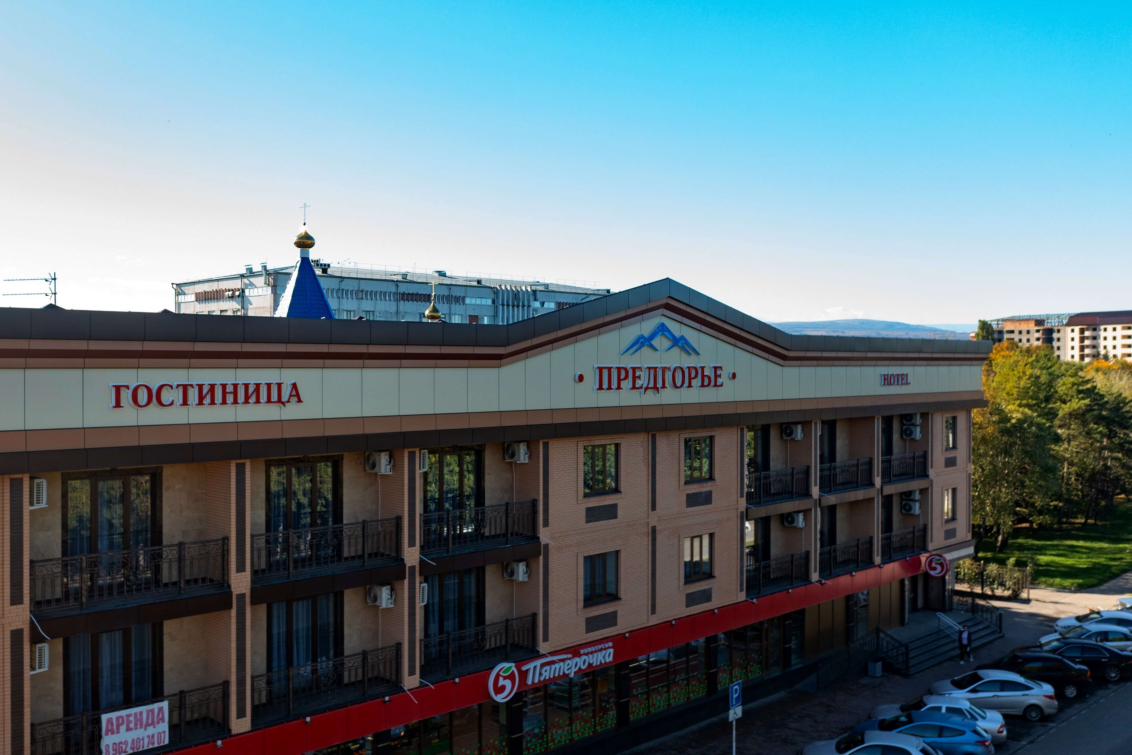Панорамный вид на центральный фасад отеля. На первом этаже расположен магазин "Пятерочка".