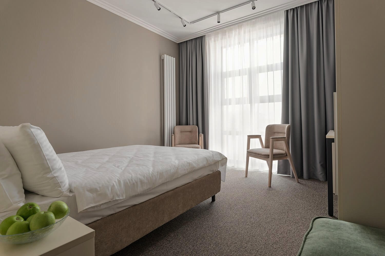 В номере большие панорамные окна, кровать застелена белоснежным бельем.
