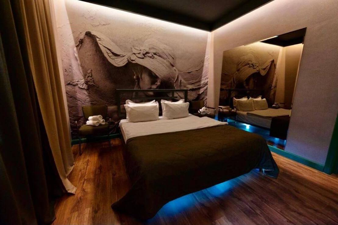 Парящая кровать с подсветкой. На стенах: картина из декоративной штукатурки и большое зеркало.