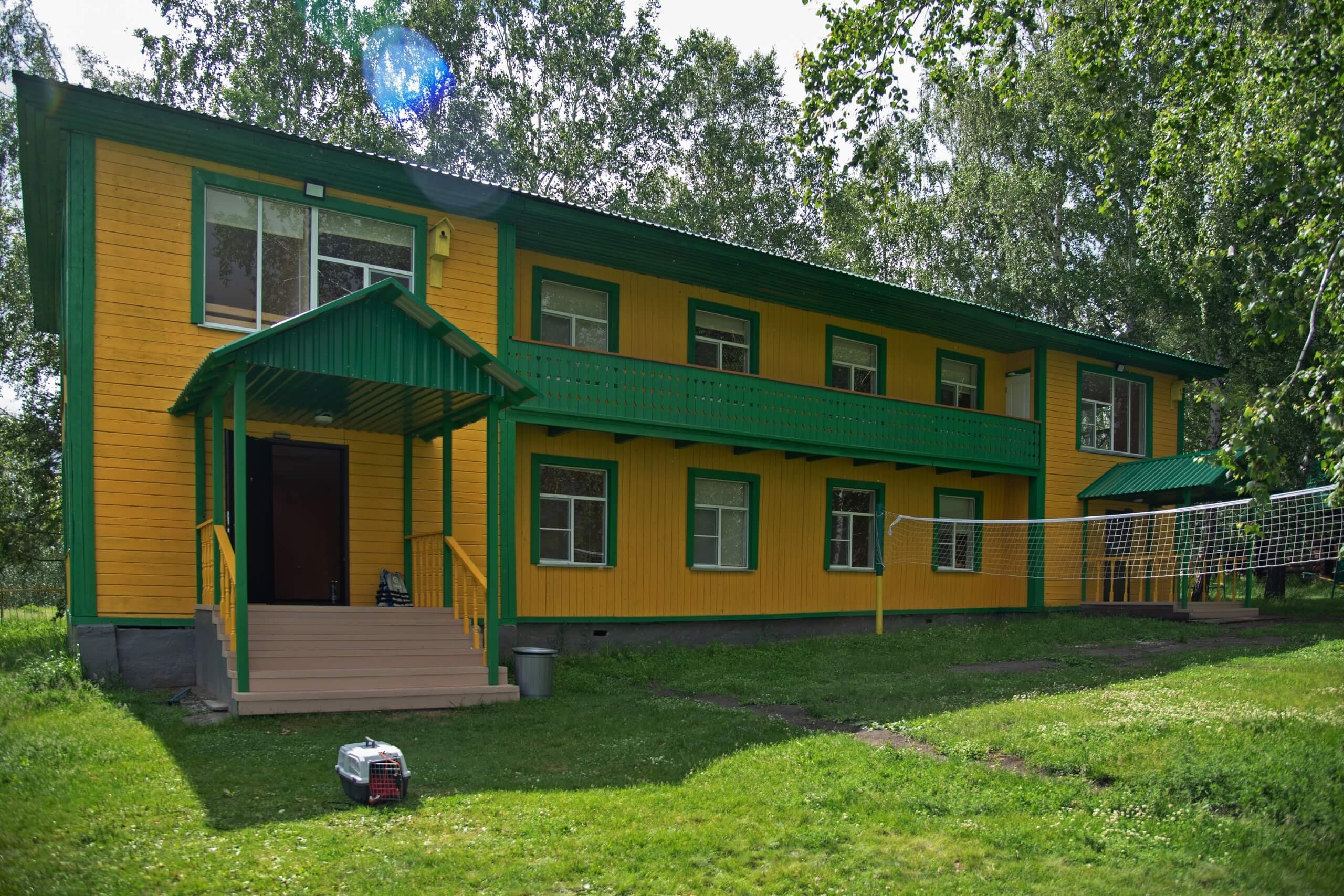 Фасад гостевого дома выкрашен в яркие желтый и зеленый цвета.