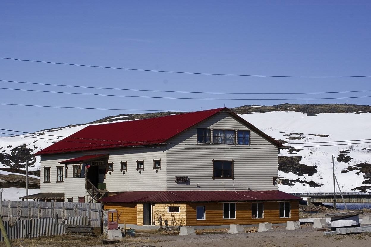 Здание отеля, с бордовой крышей, на фоне местных пейзажей.