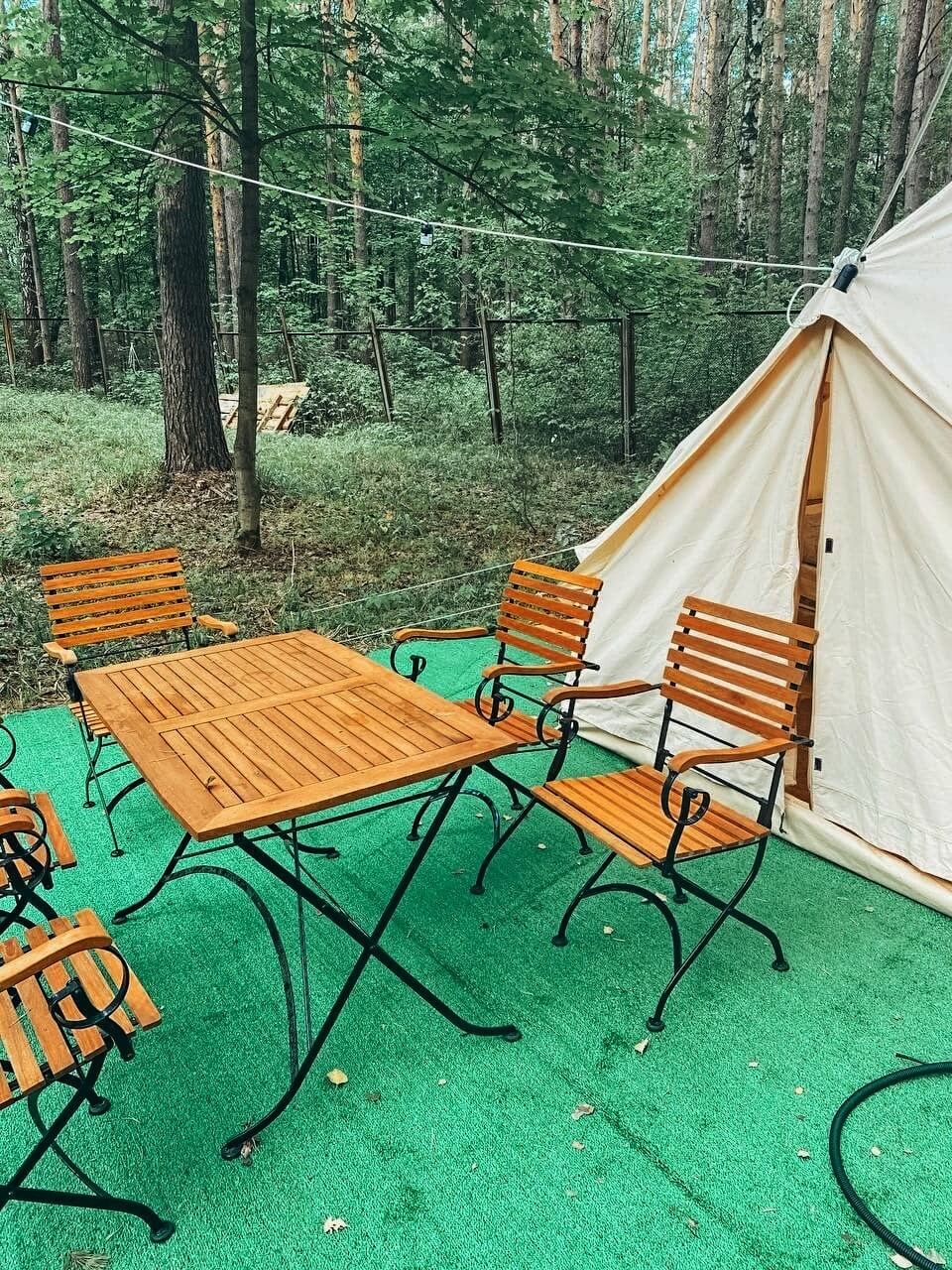 Зона отдыха перед палаткой: столик и пять стульев.