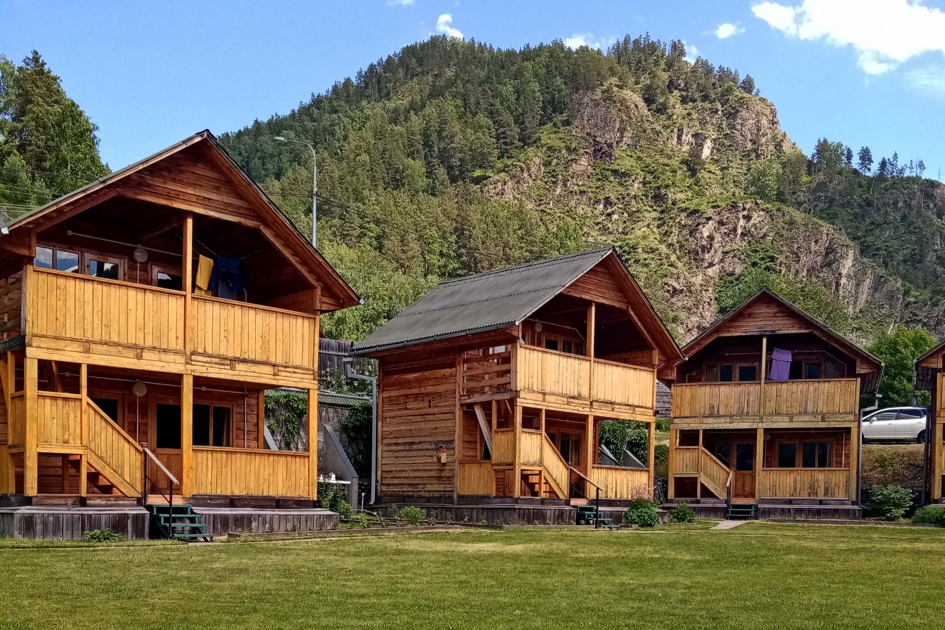 Три больших деревянных дома в горах Алтая.