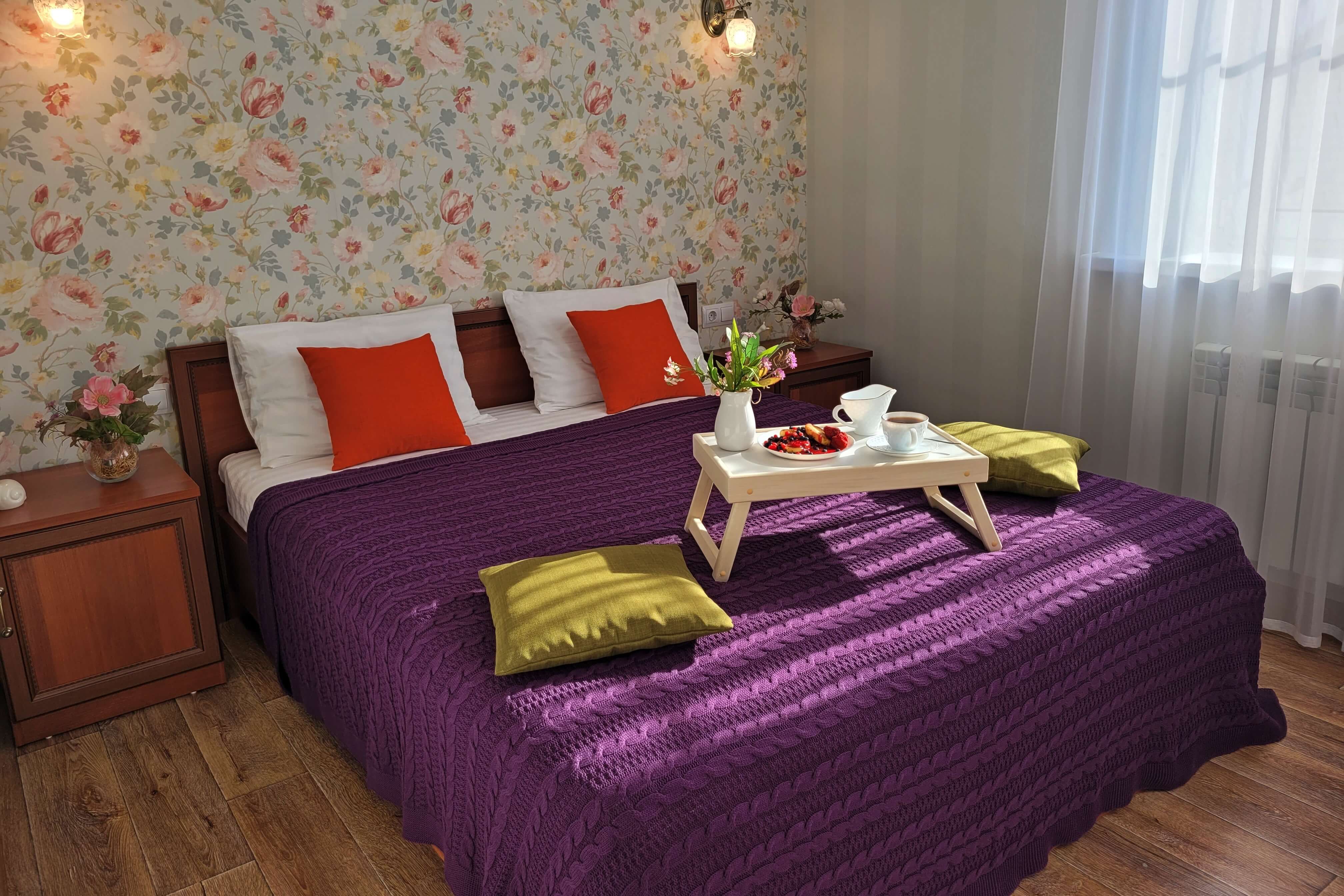 Кровать застелена вязаным фиолетовым пледом.