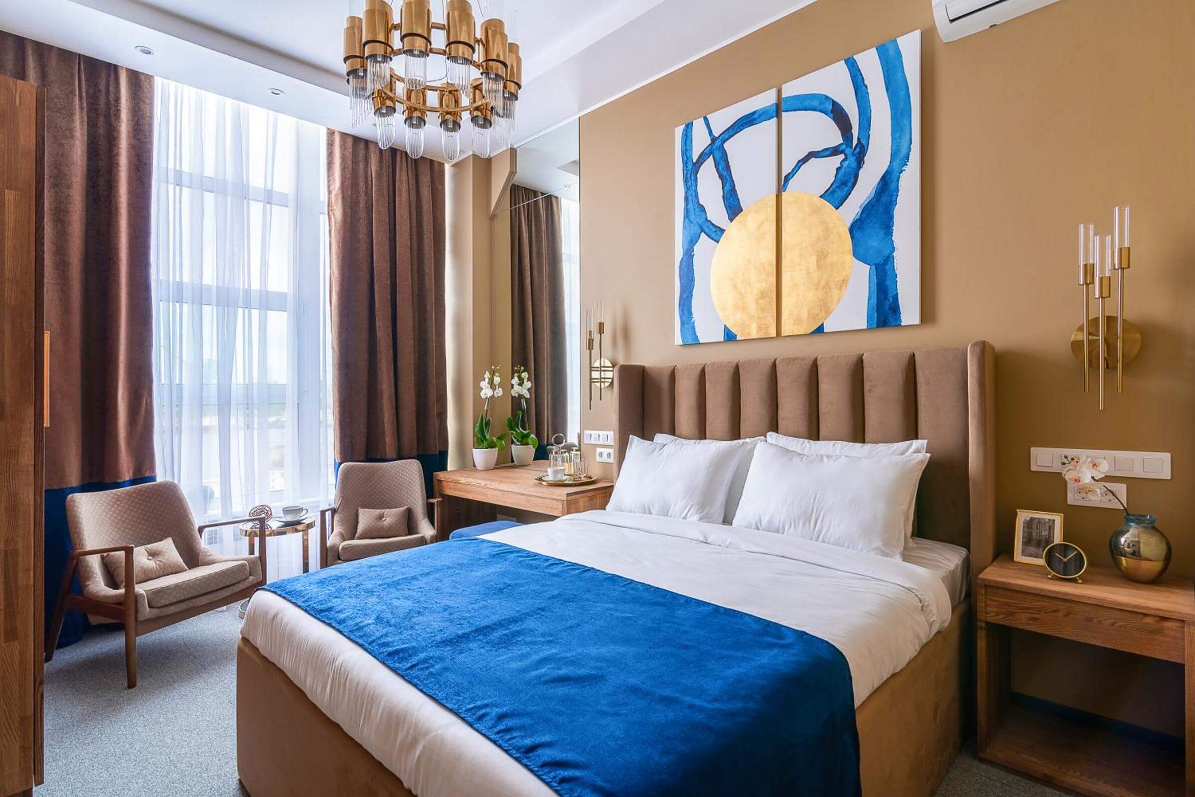Стену украшает оригинальное "современное искусство", кровать застелена синим саше.