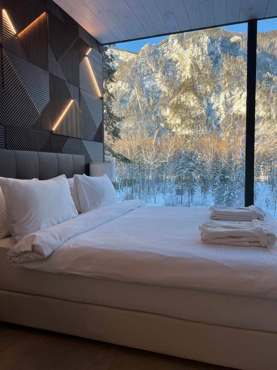Кровать с белоснежным бельем и большое панорамное окно.