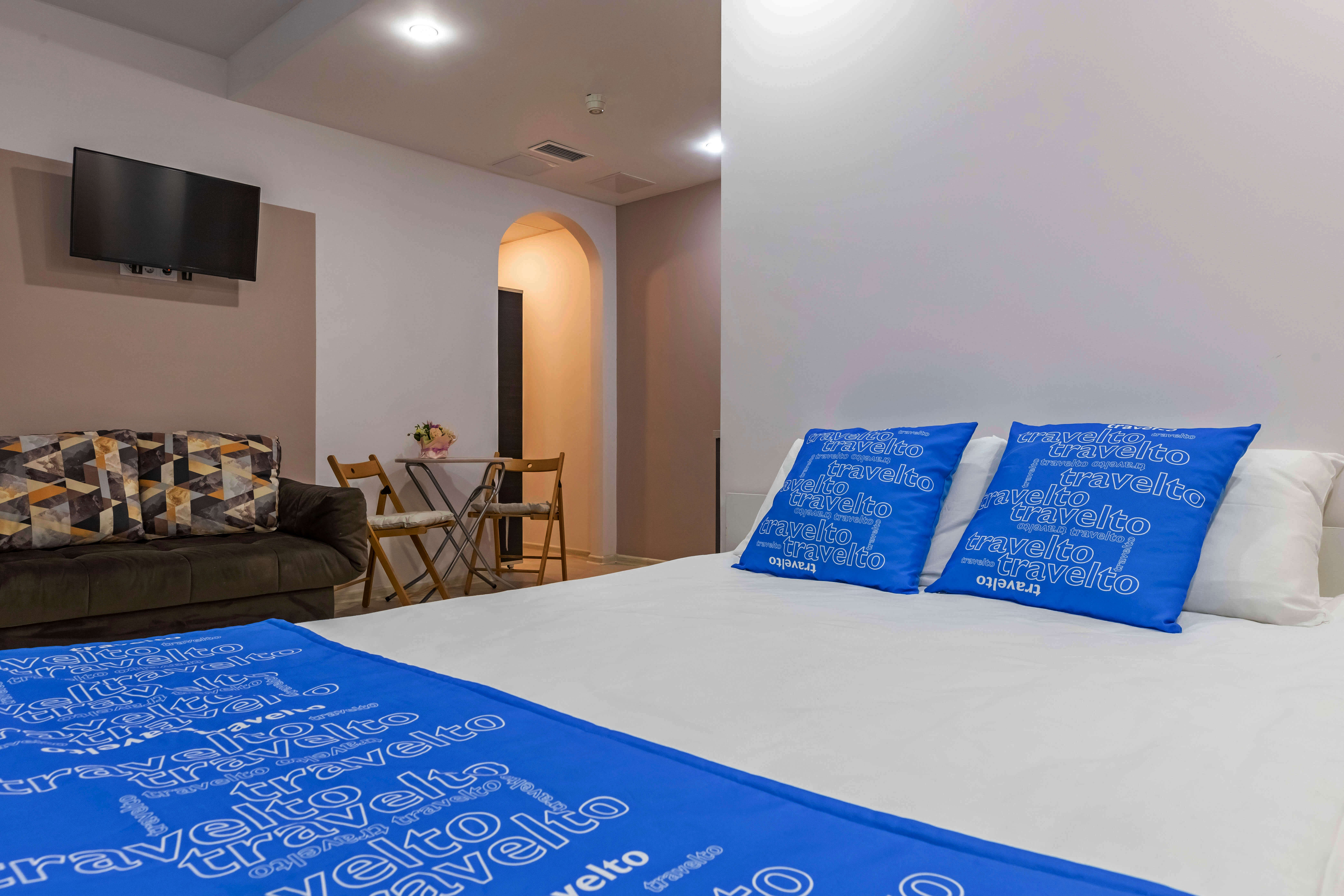 Кровать украшают подушки и синее саше с принтом: Travelto.