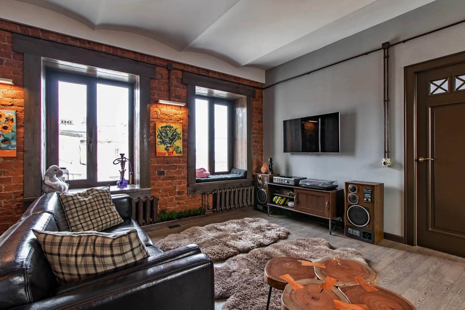 Зона гостиной: черный кожаный диван и телевизор.