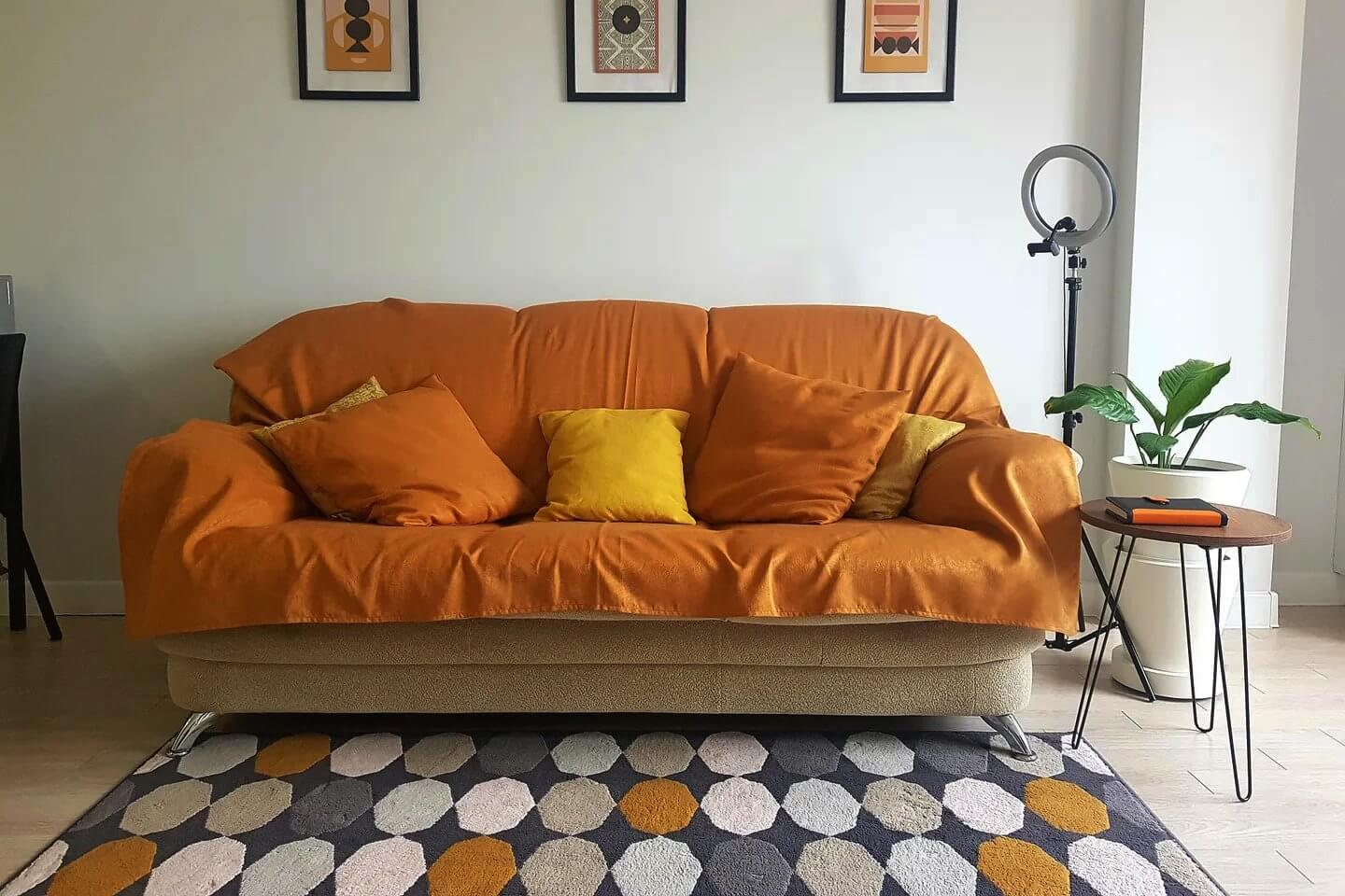 Красивый диван с ярким оранжевым покрывалом.