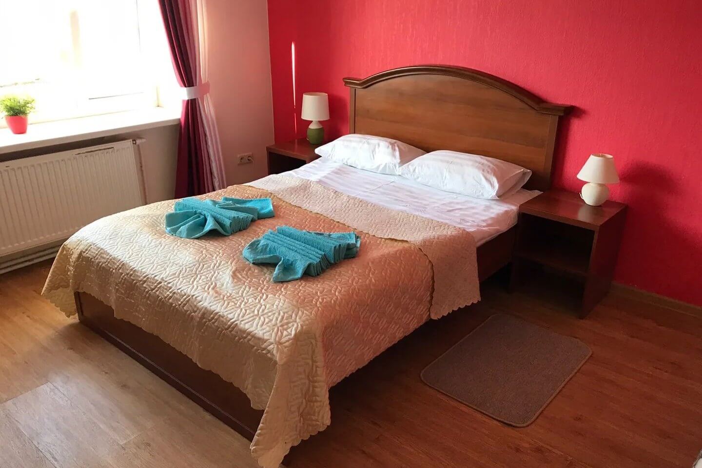 Кровать. Розовая стена. Голубые полотенца.