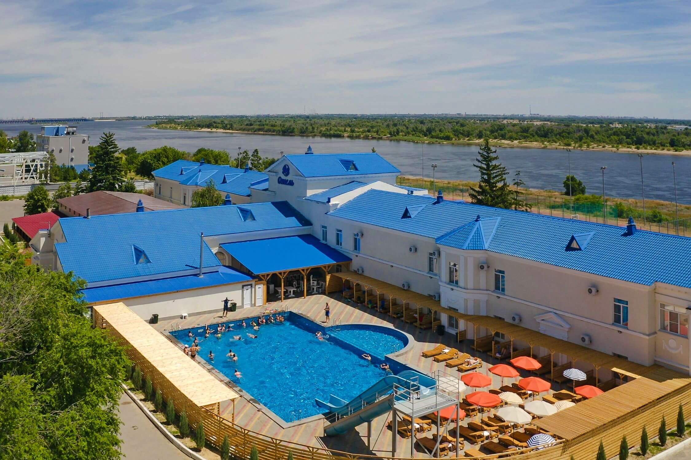 Панорамный вид: бассейн, синяя крыша отеля и Волга.