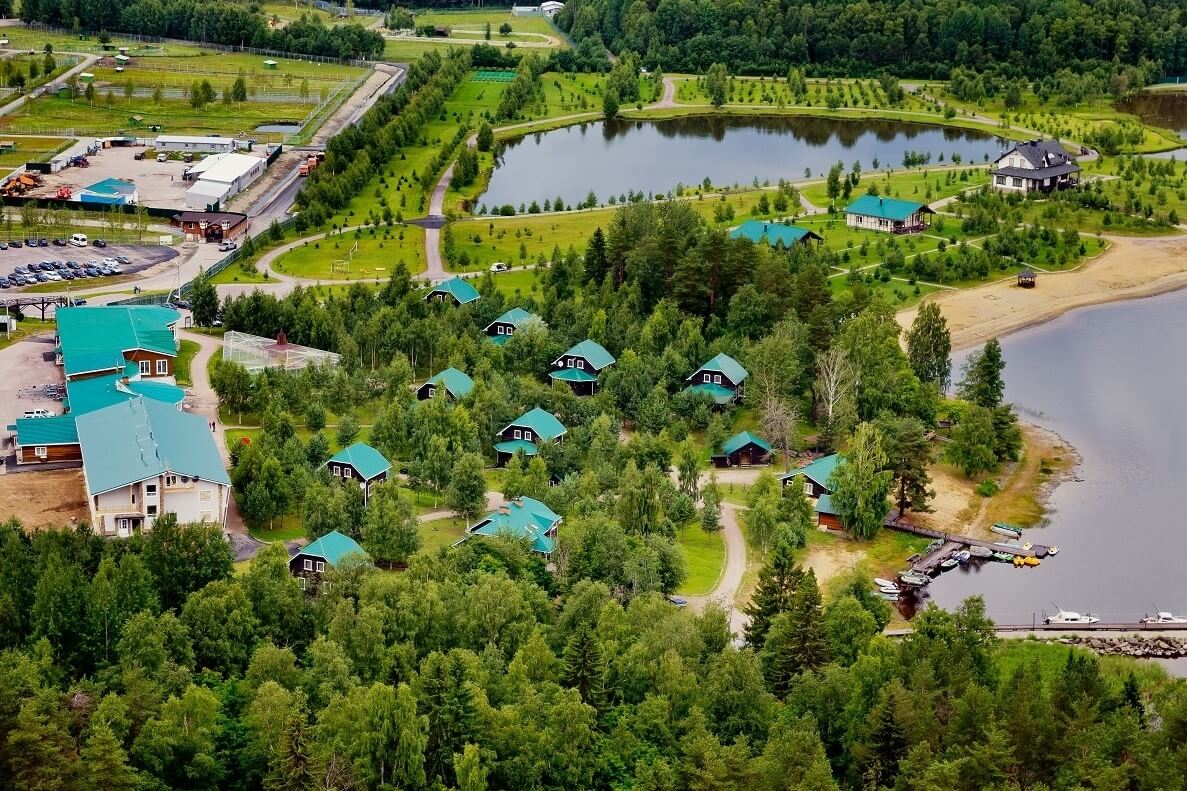 Панорамный вид: озеро, зеленый лес и крыши домов.