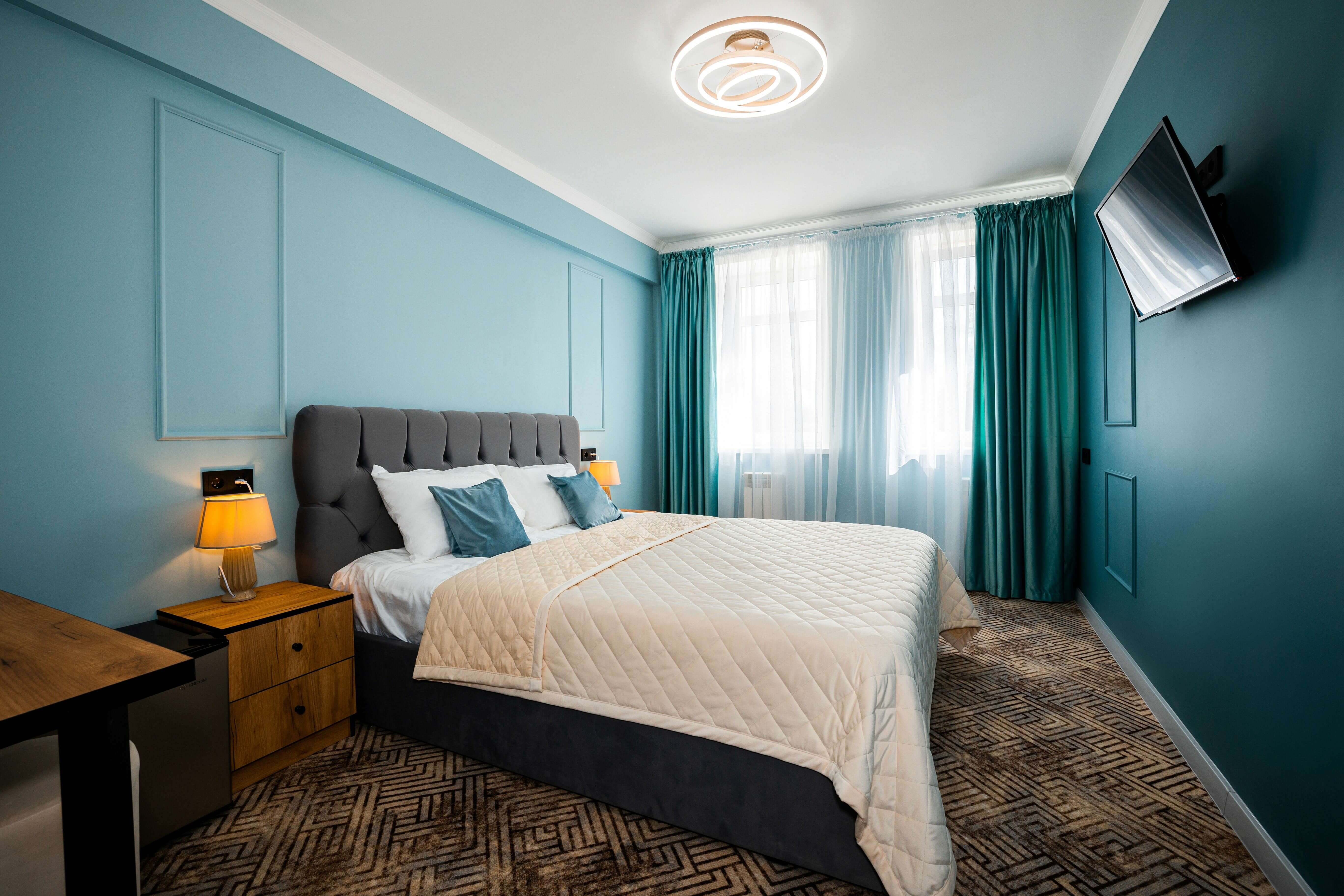 В номере большая кровать, шторы и стены - бирюзово-синих цветов.