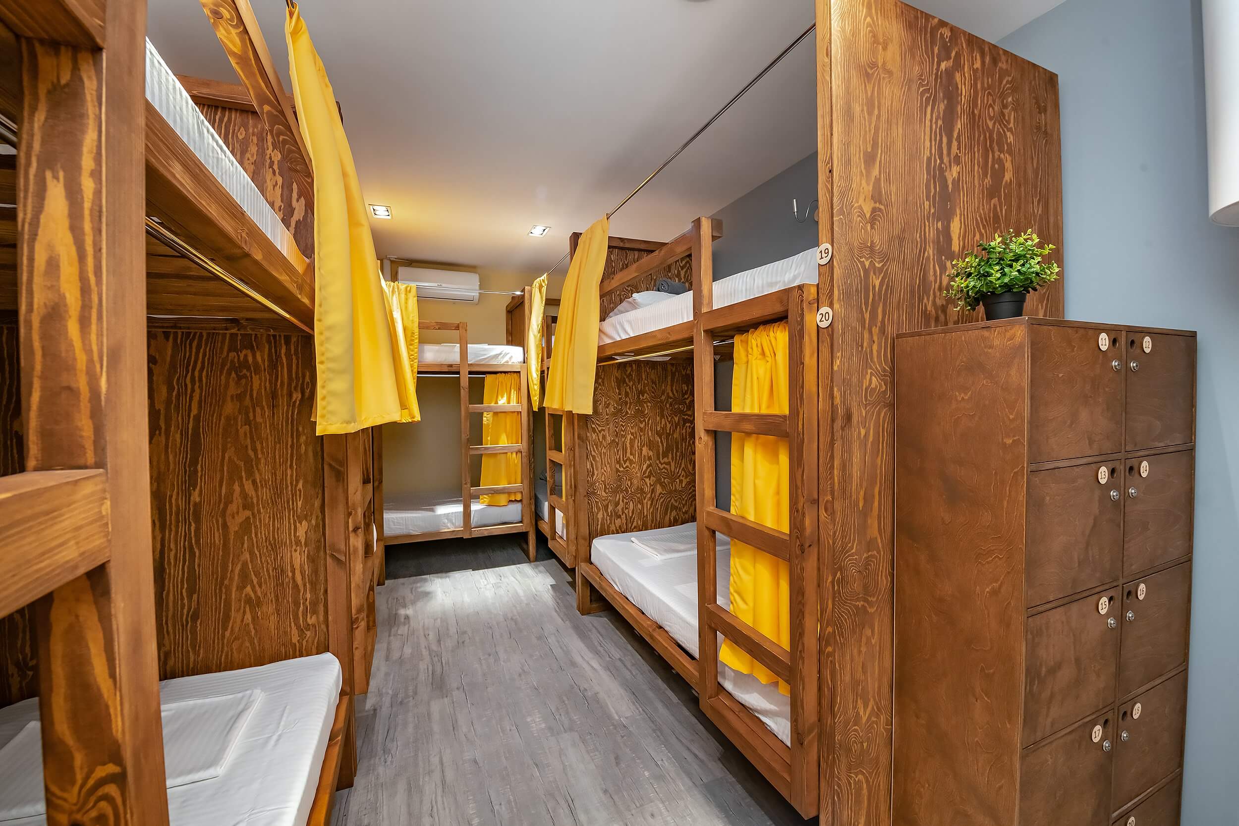 Красивые, деревянные кровати укомплектованы желтыми шторками.
