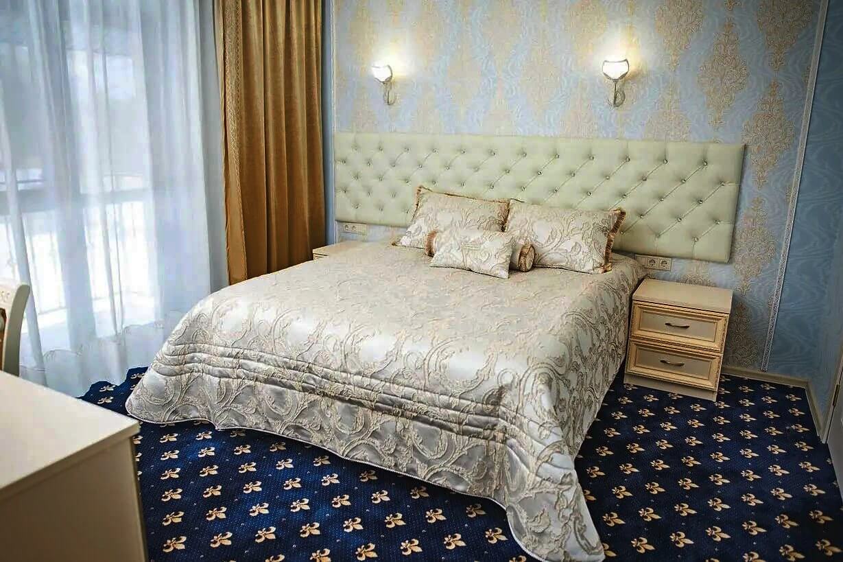 Заправленная кровать и классический гостиничный ковролин.