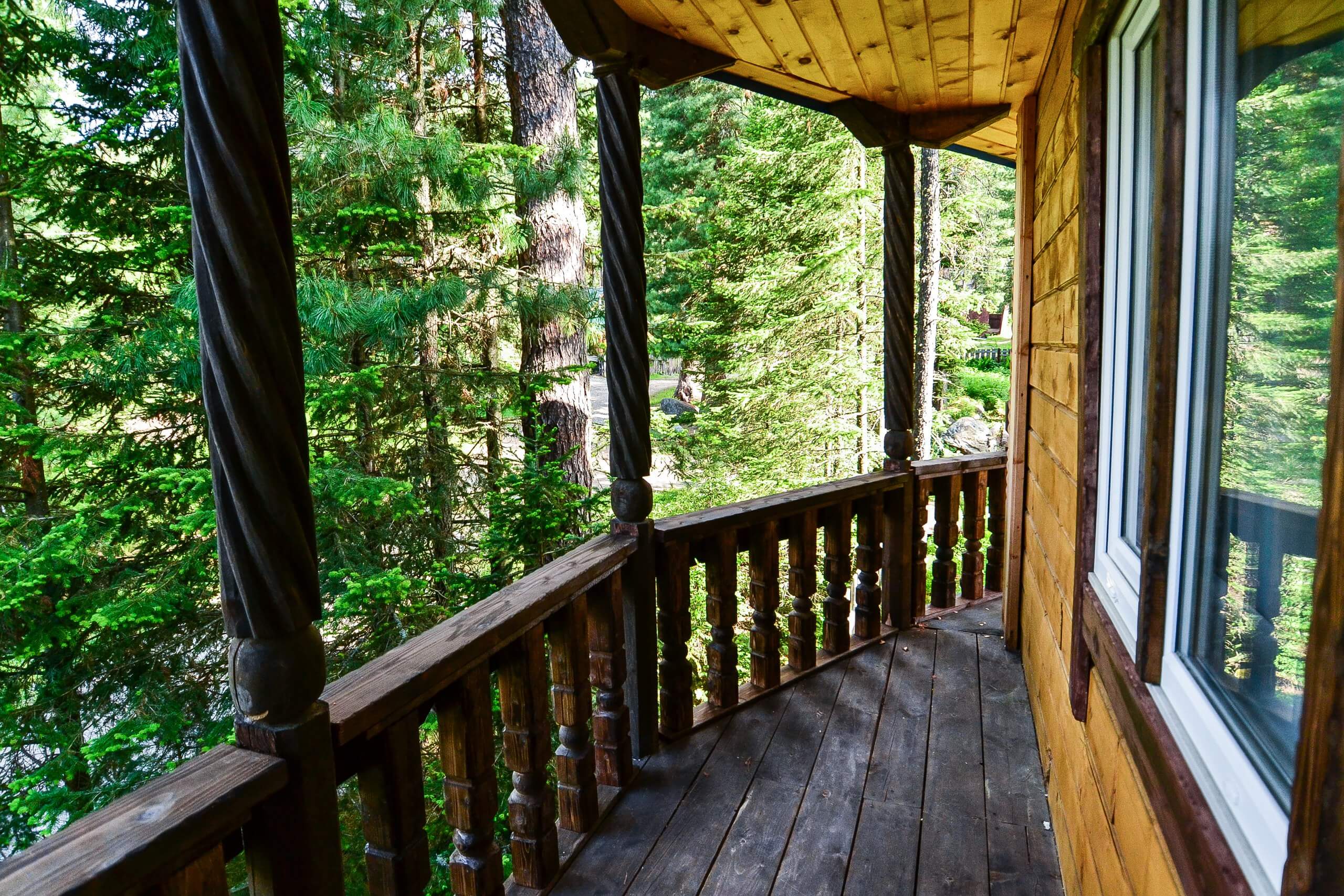 Деревянный балкон с красивой балюстрадой. Вид - на зеленый лес.