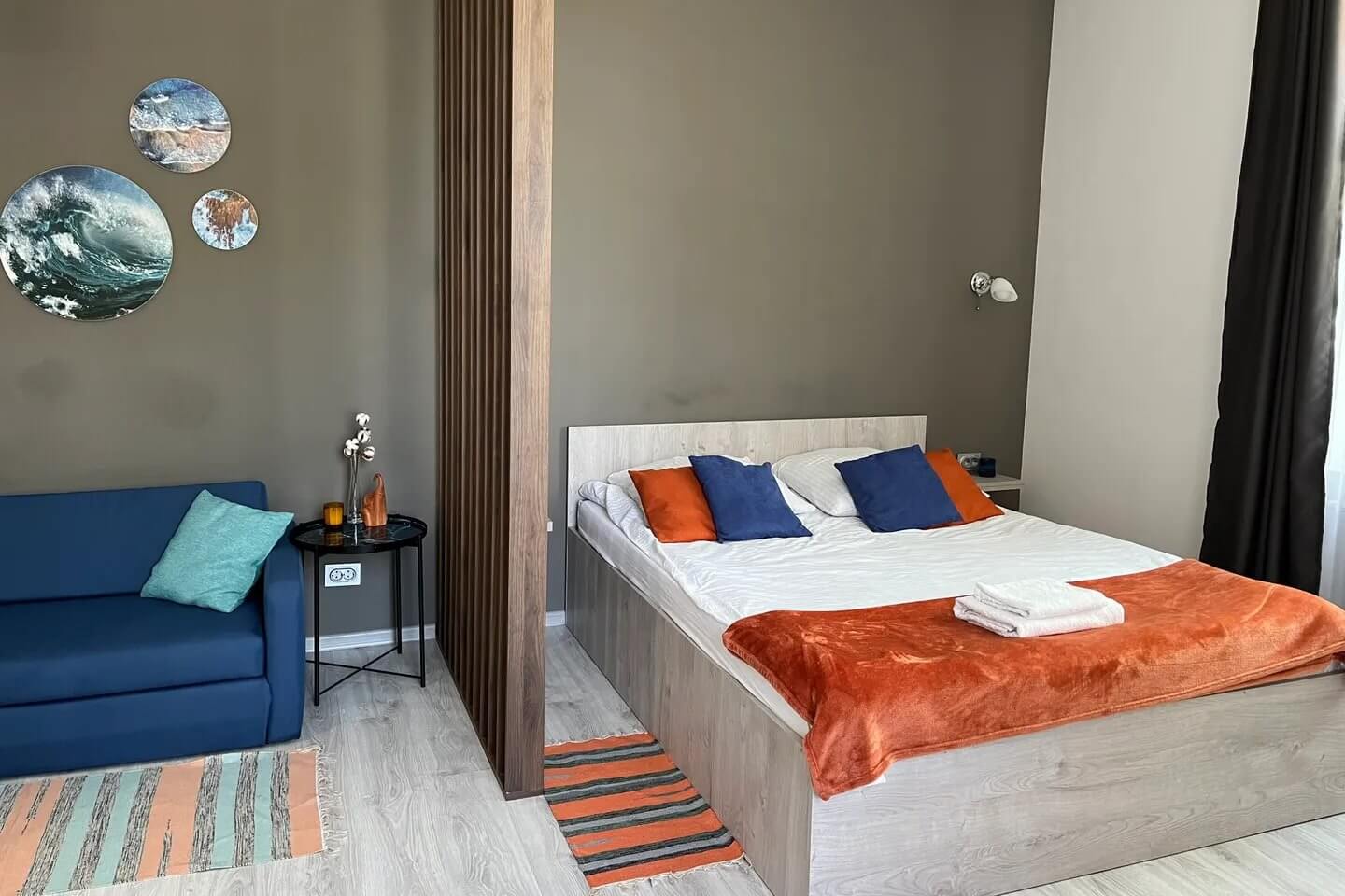 Спальное место в комнате отделено деревянной перегородкой. На кровати саше мандаринового цвета.