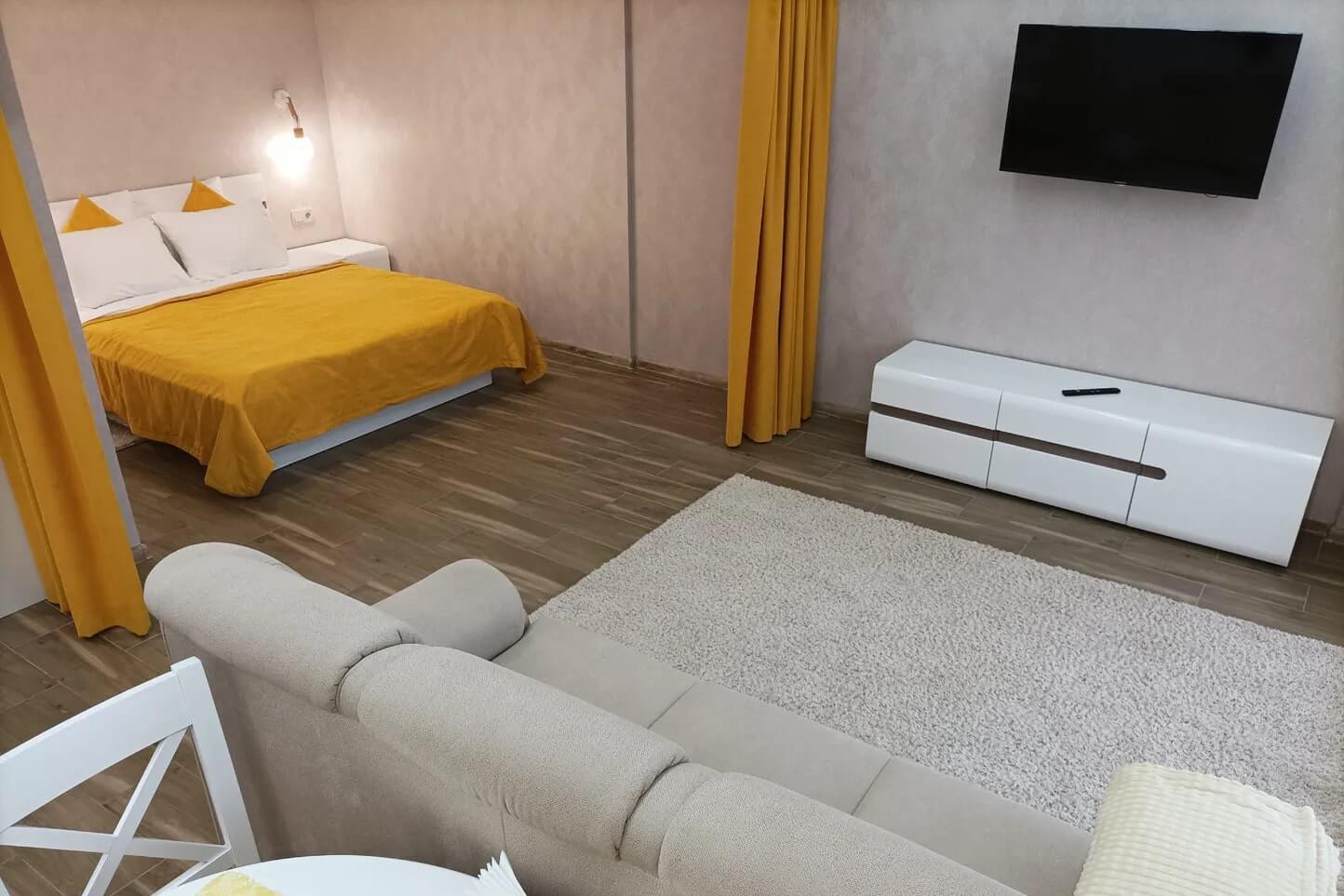 Для визуального ограждения спальни использованы желтые шторки.