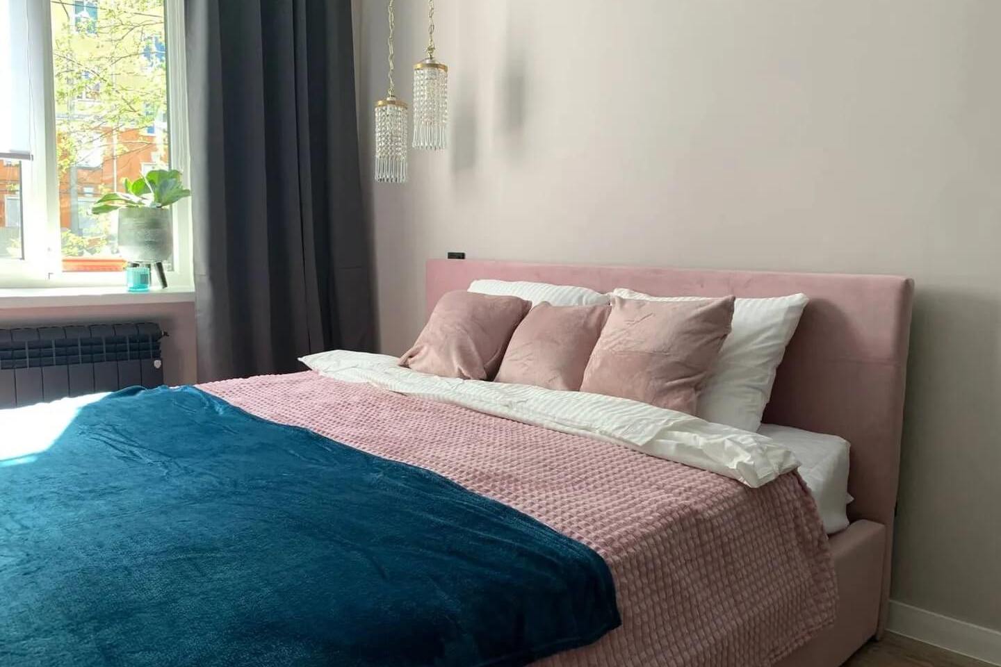 Основание кровати, одеяло и подушки - розового цвета.
