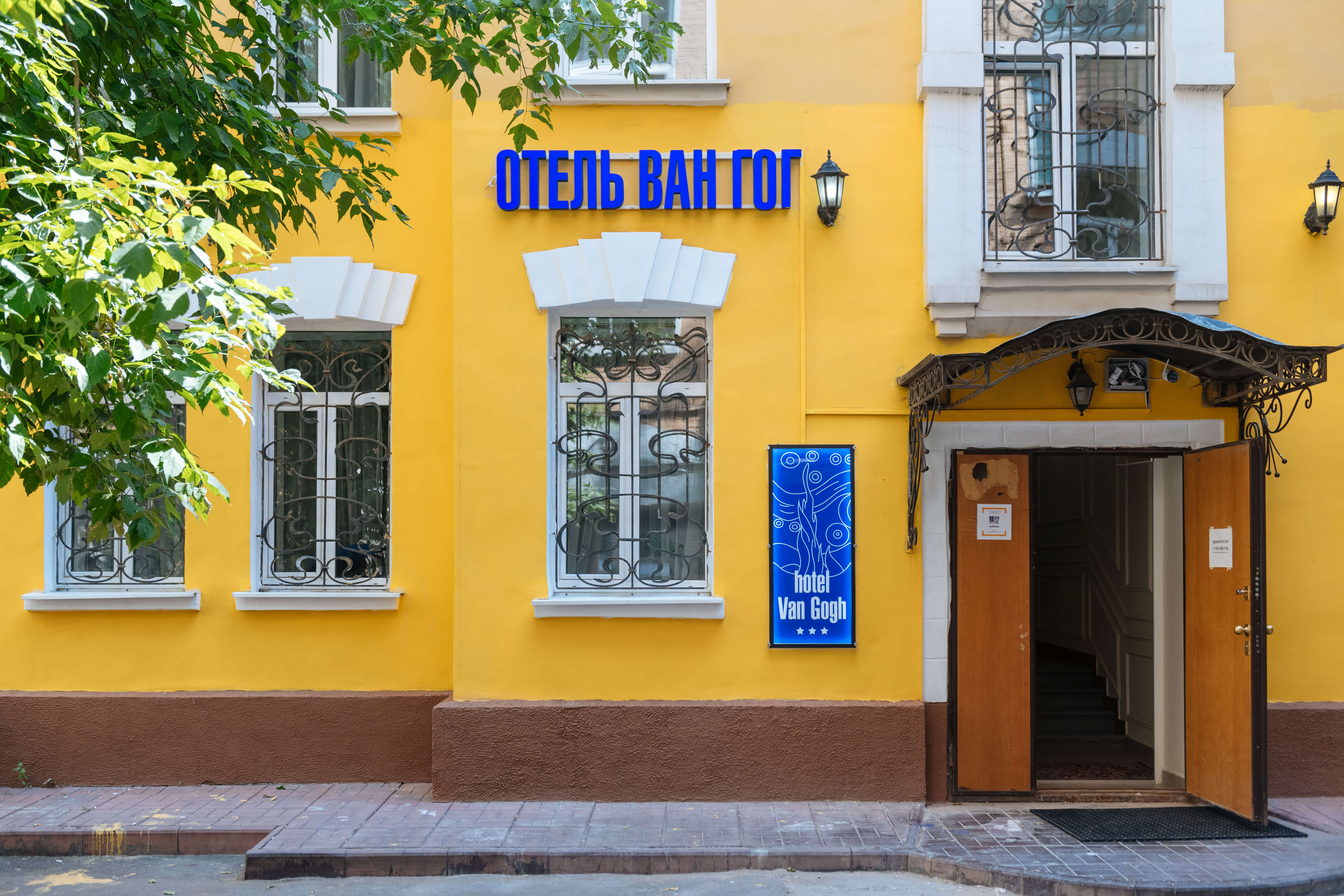 На желтом фасаде хорошо видна синяя вывеска: ОТЕЛЬ ВАН ГОГ.
