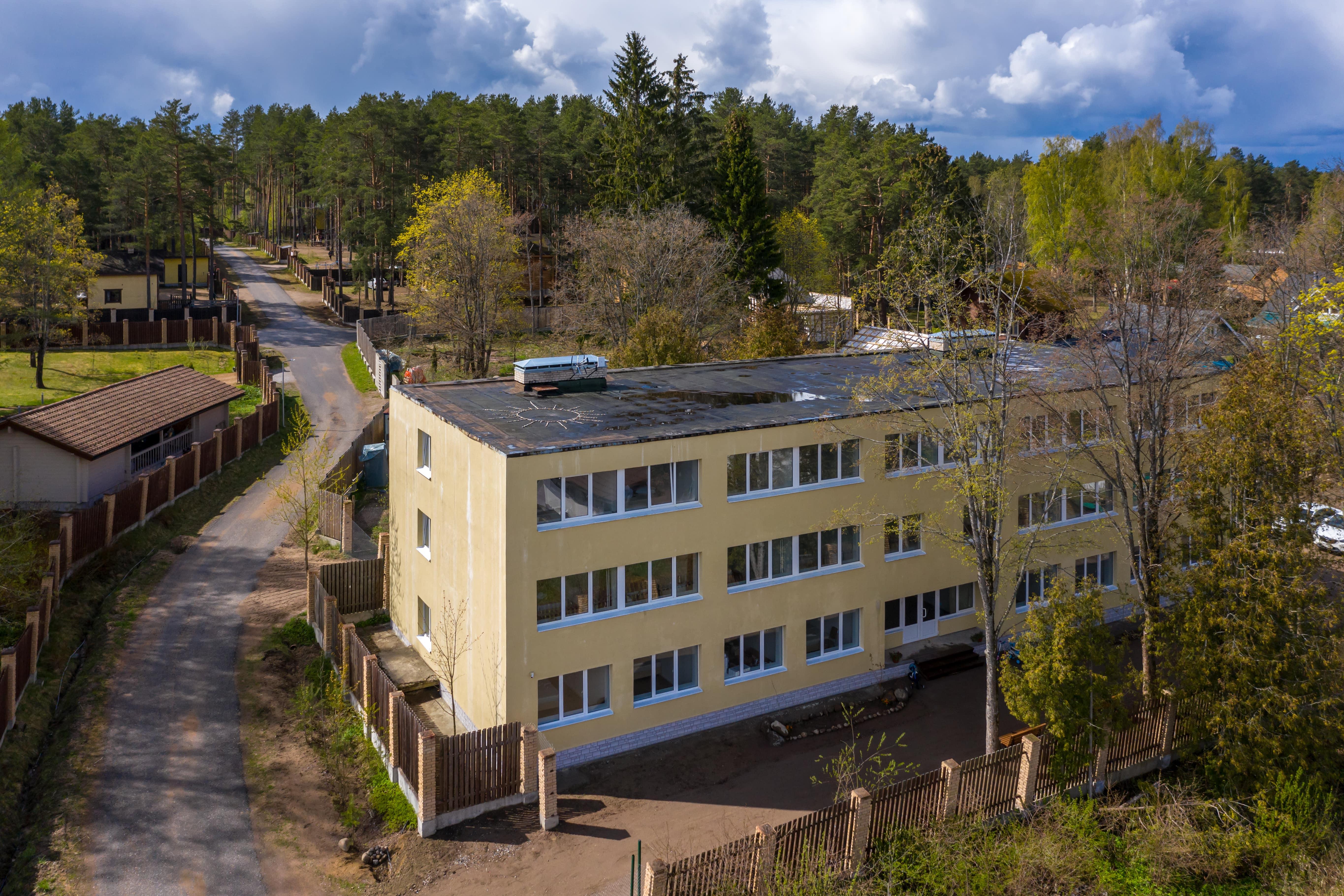 Панорамный вид: здание гостиницы, лес и дорога.
