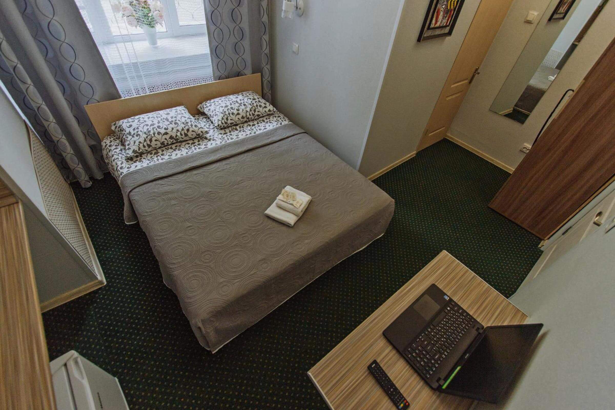 Вид на номер: кровать, стол с ноутбуком.