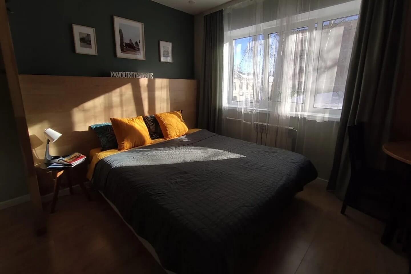 Кровать установлена возле окна. Подушки - желтые.