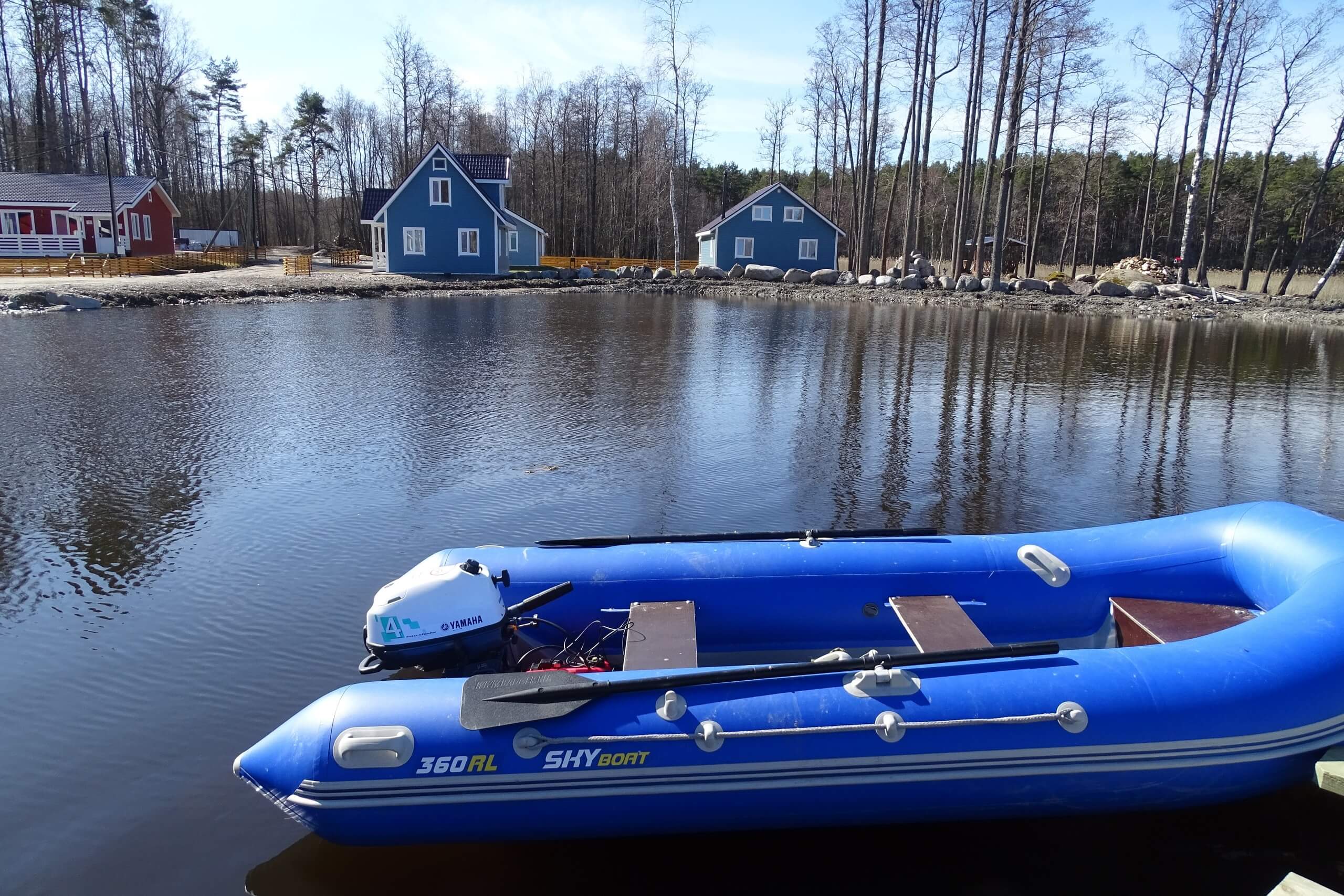Домики на берегу и синяя надувная лодка с мотором.