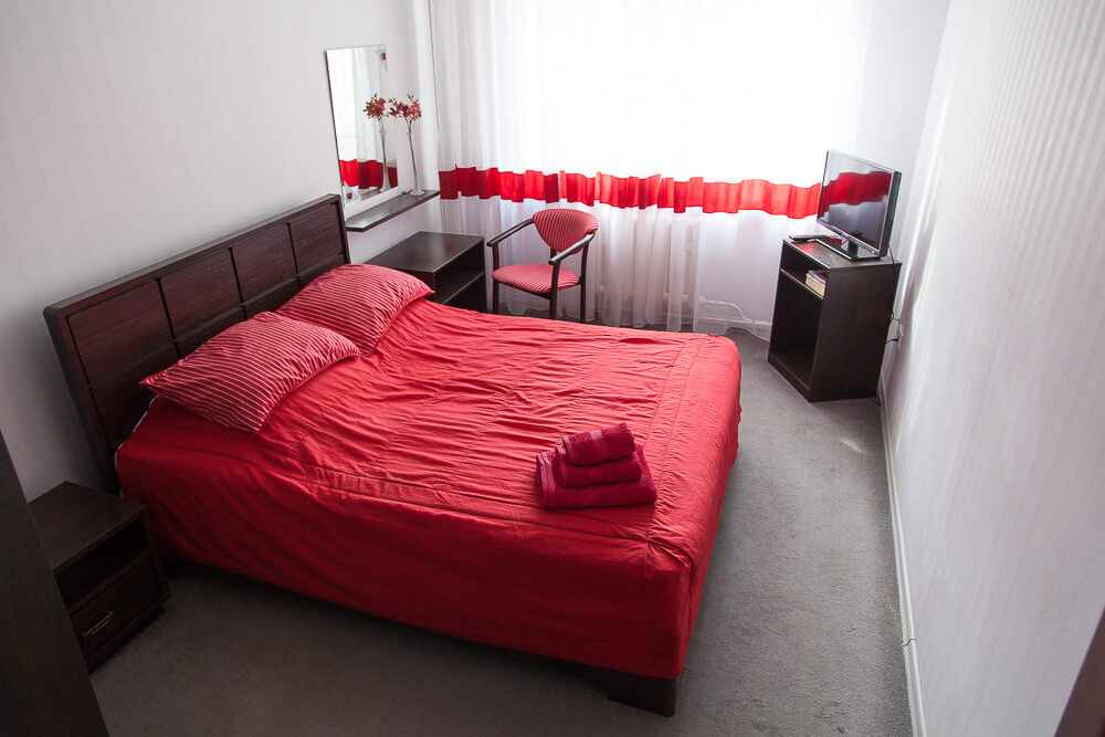 Кровать застелена ярким красным покрывалом.