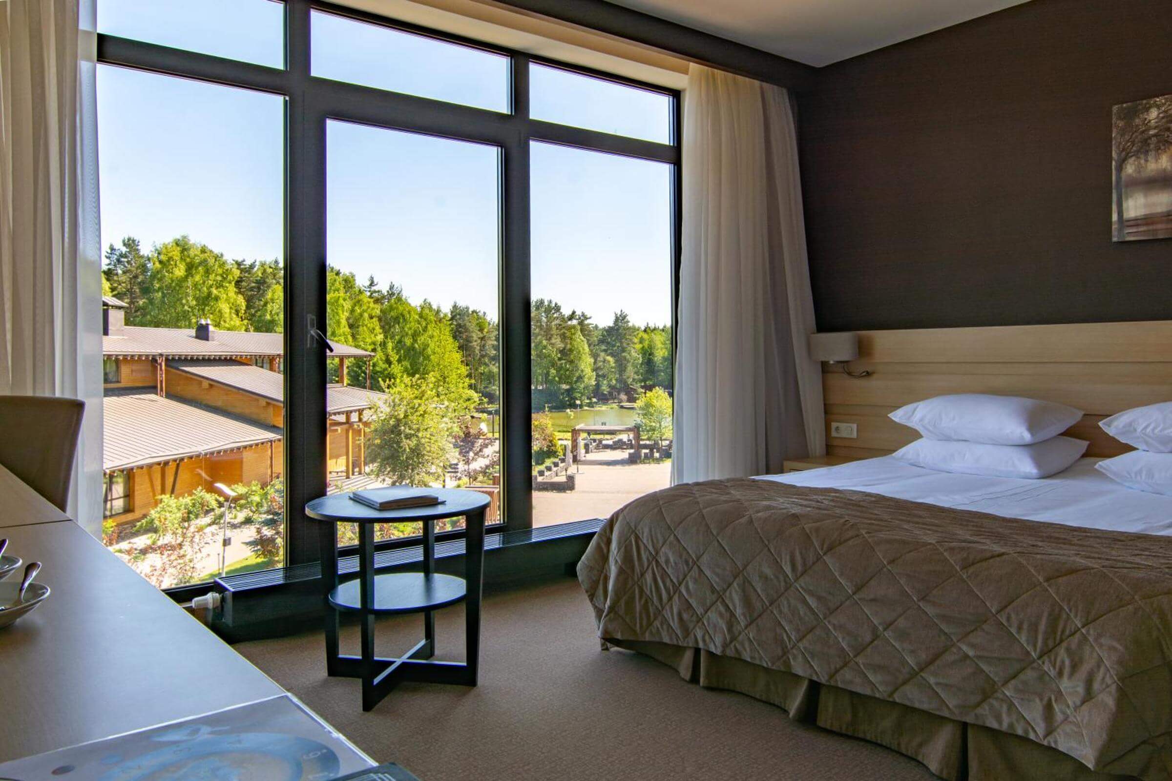 Кровать в номере установлена рядом с большим панорамным окном.