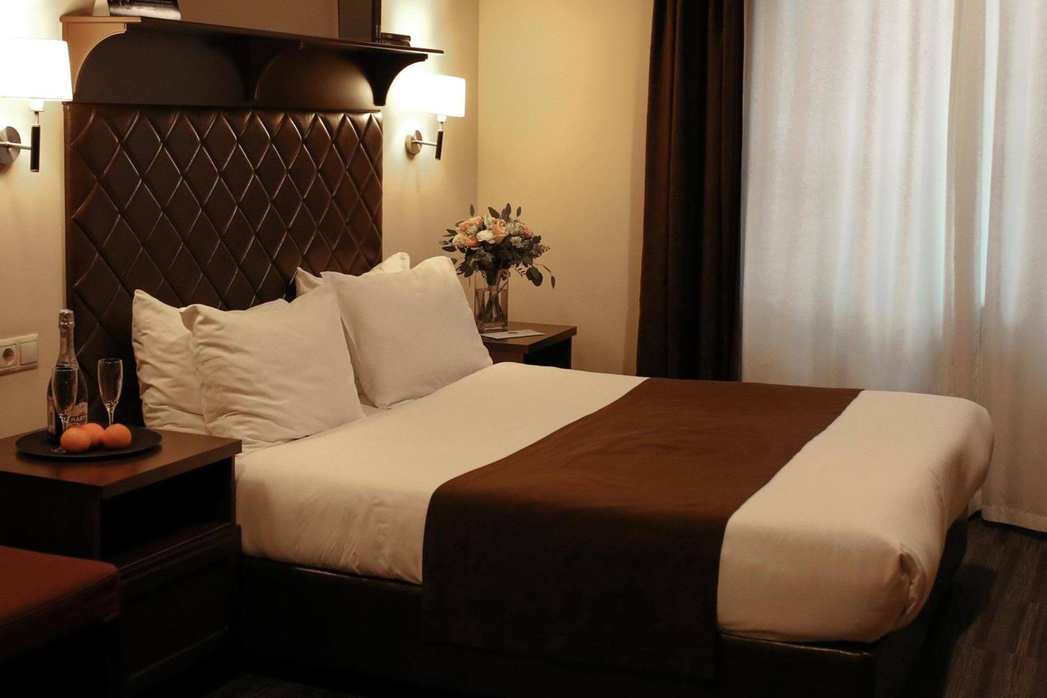 Спальня: коричневое саше на кровати, шампанское и фрукты на тумбочке.