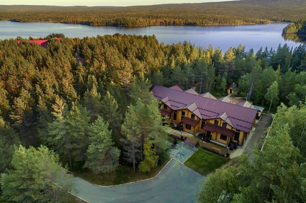 Панорамный вид: лес, озеро и большой гостевой дом.