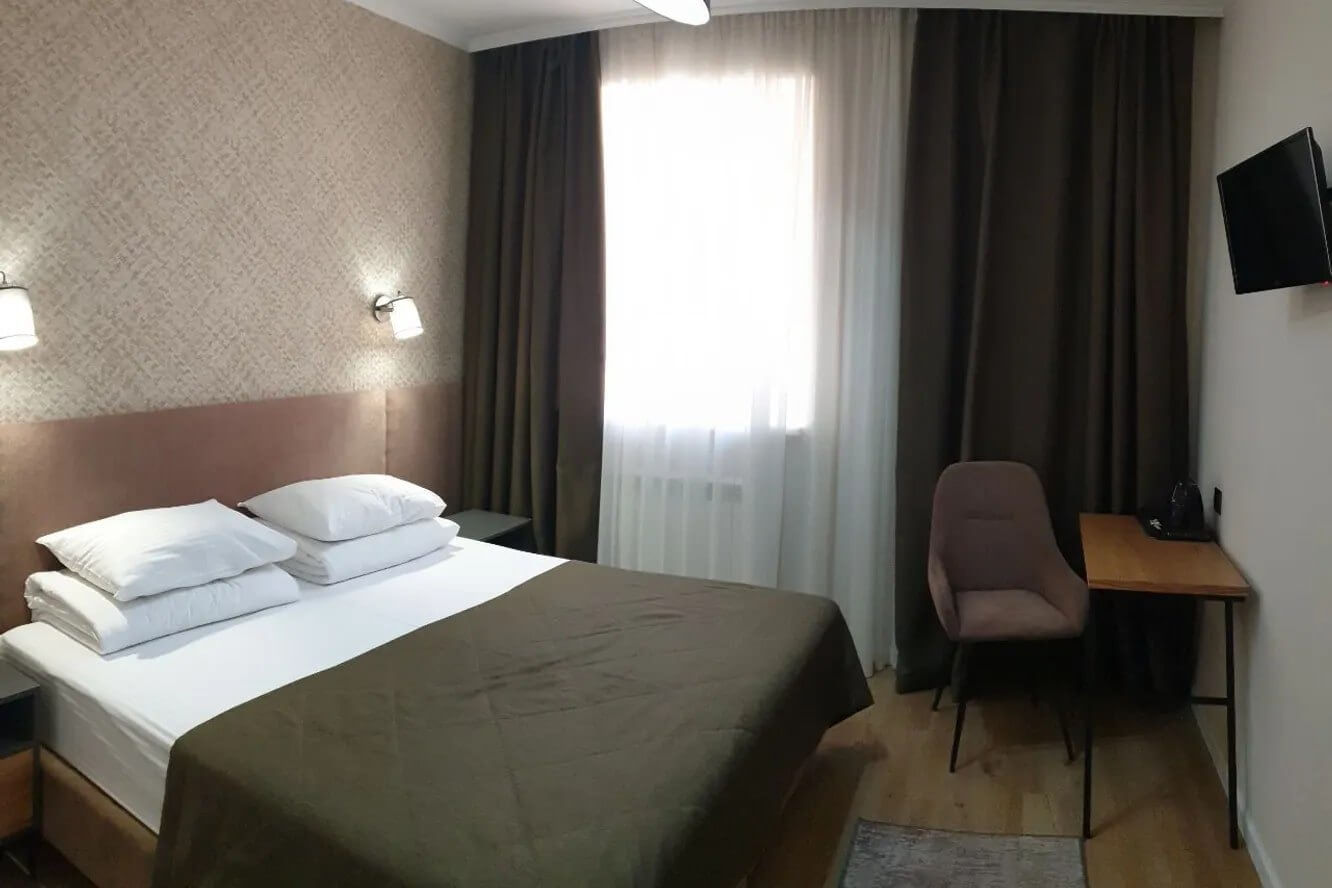 Отель «Альпина». Гостиничный номер: кровать и небольшой столик.