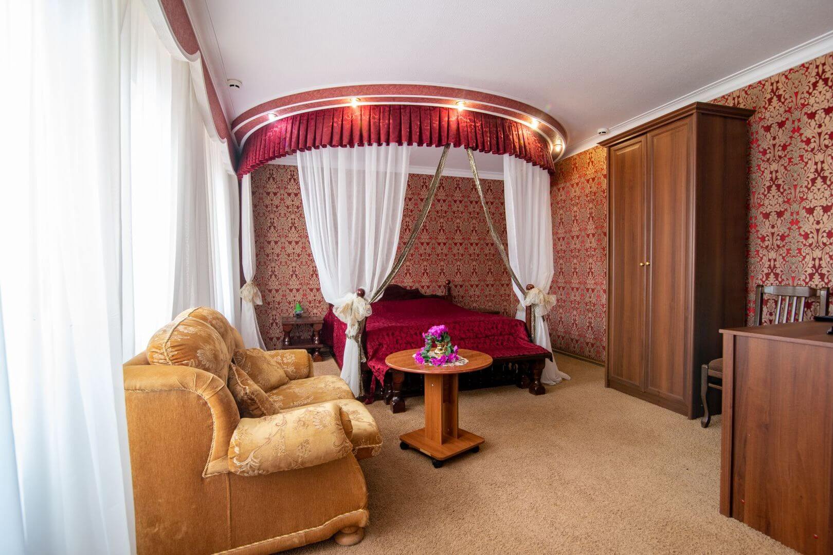 Отель «Шахерезада». Номер: кровать с балдахином, большой диван и журнальный столик.