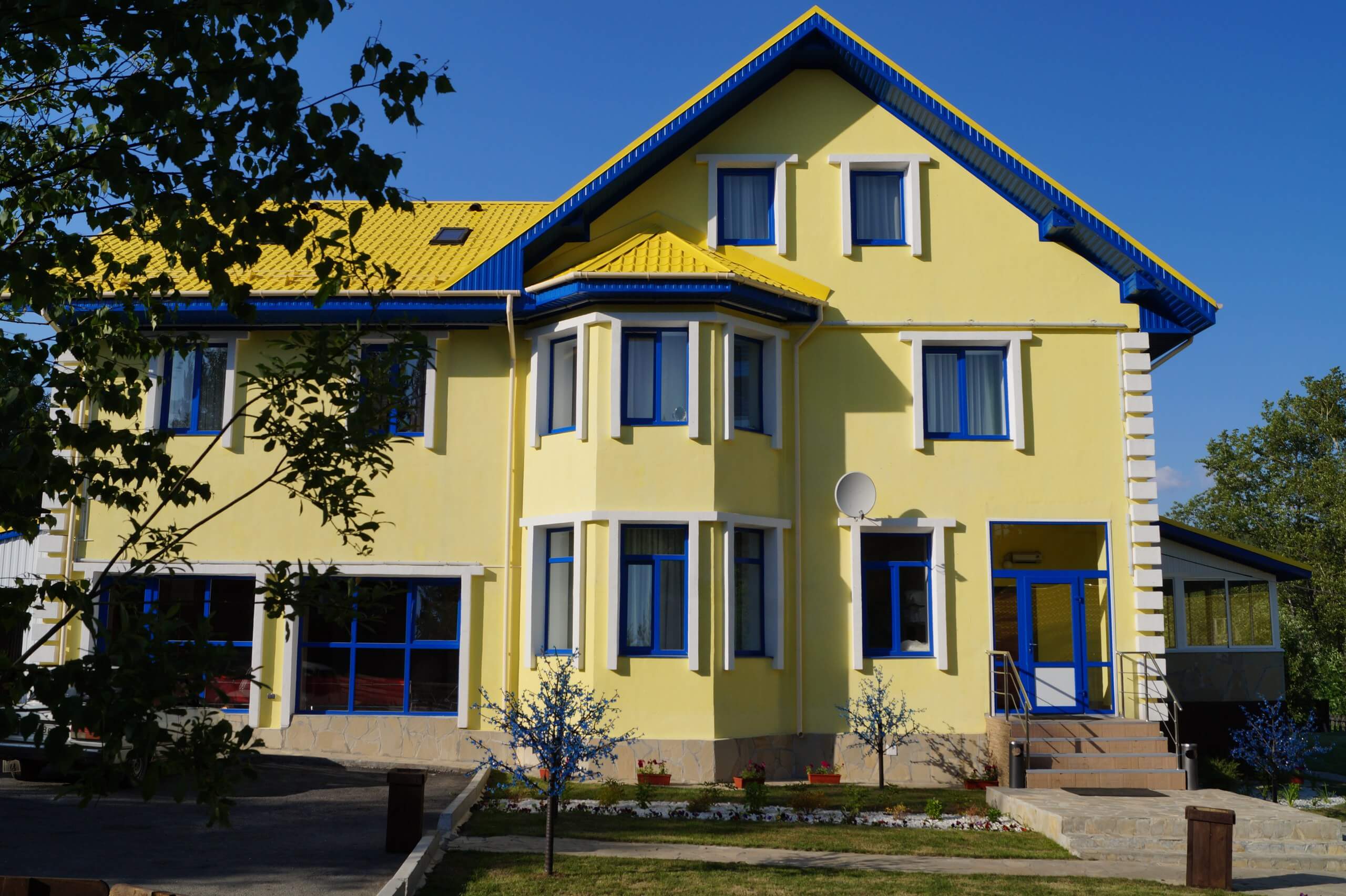Фасад отеля окрашен в яркий желтый цвет. Оконные рамы - синие.
